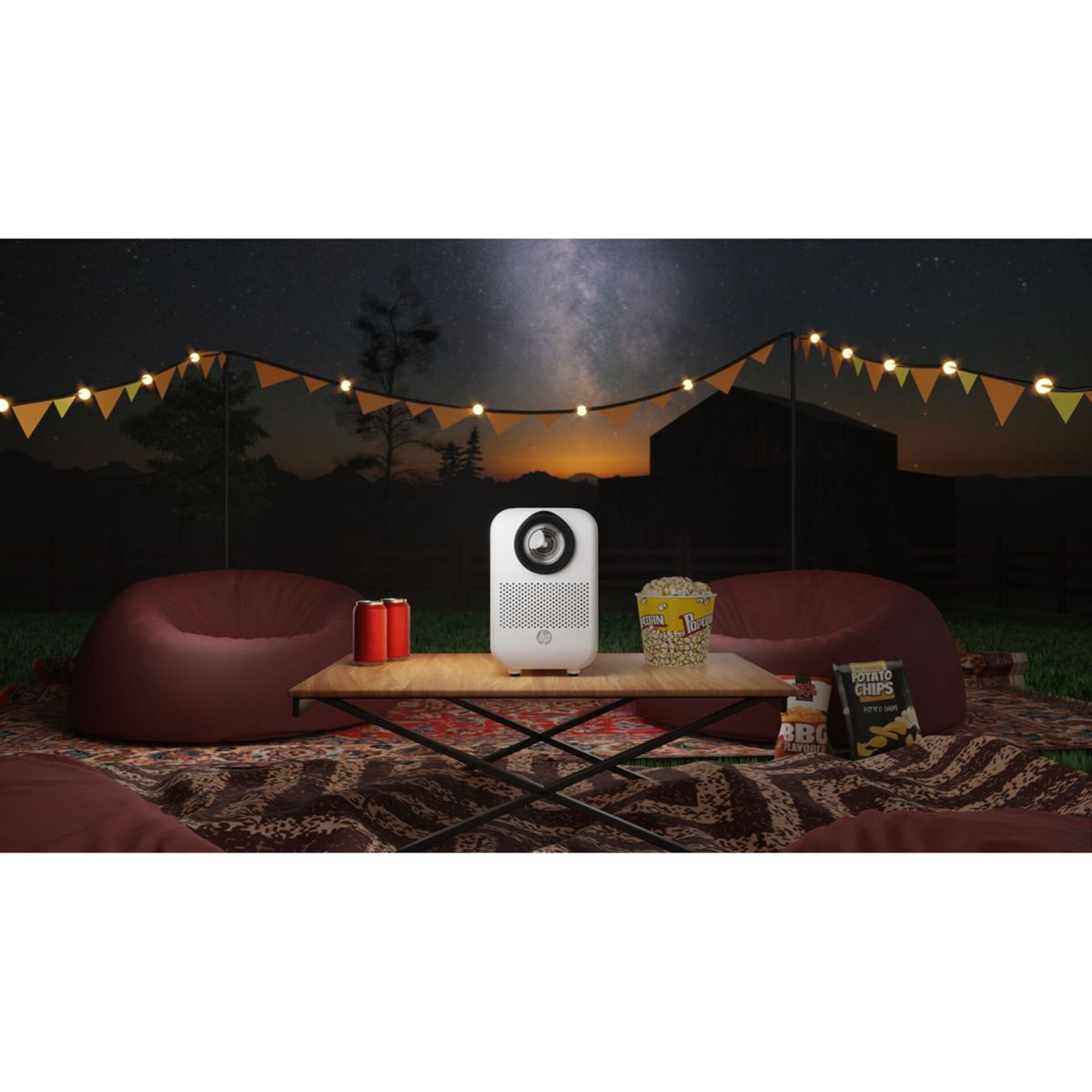 Eine Projektor-Installation im Freien bei Nacht. Enthält einen Projektor, Popcorn, Getränke, Sitzsäcke und einen Sternenhimmel mit Lichterketten.