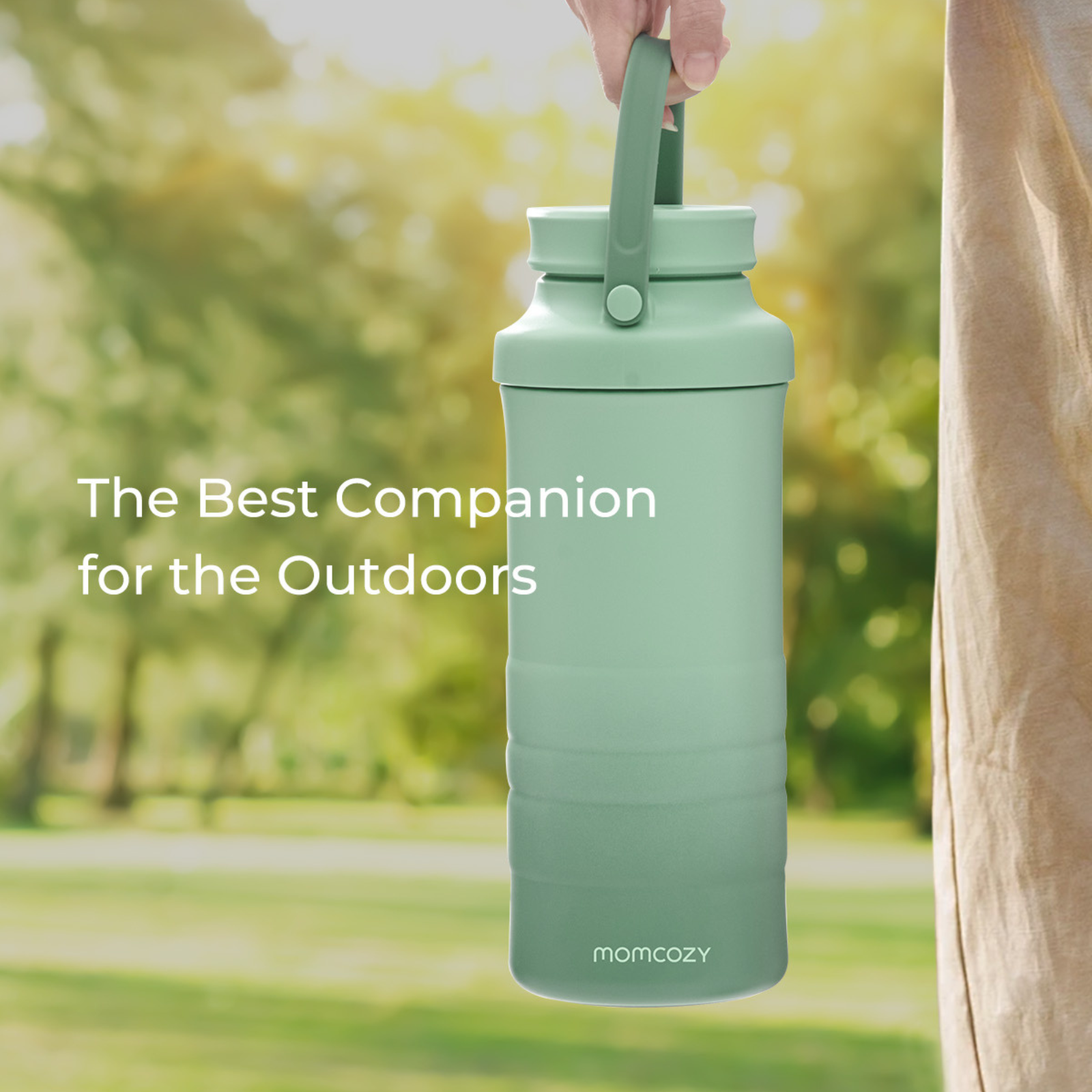 Une bouteille d'eau verte est tenue à l'extérieur. Elle a une poignée et les mots 'Le meilleur compagnon pour l'extérieur'.
