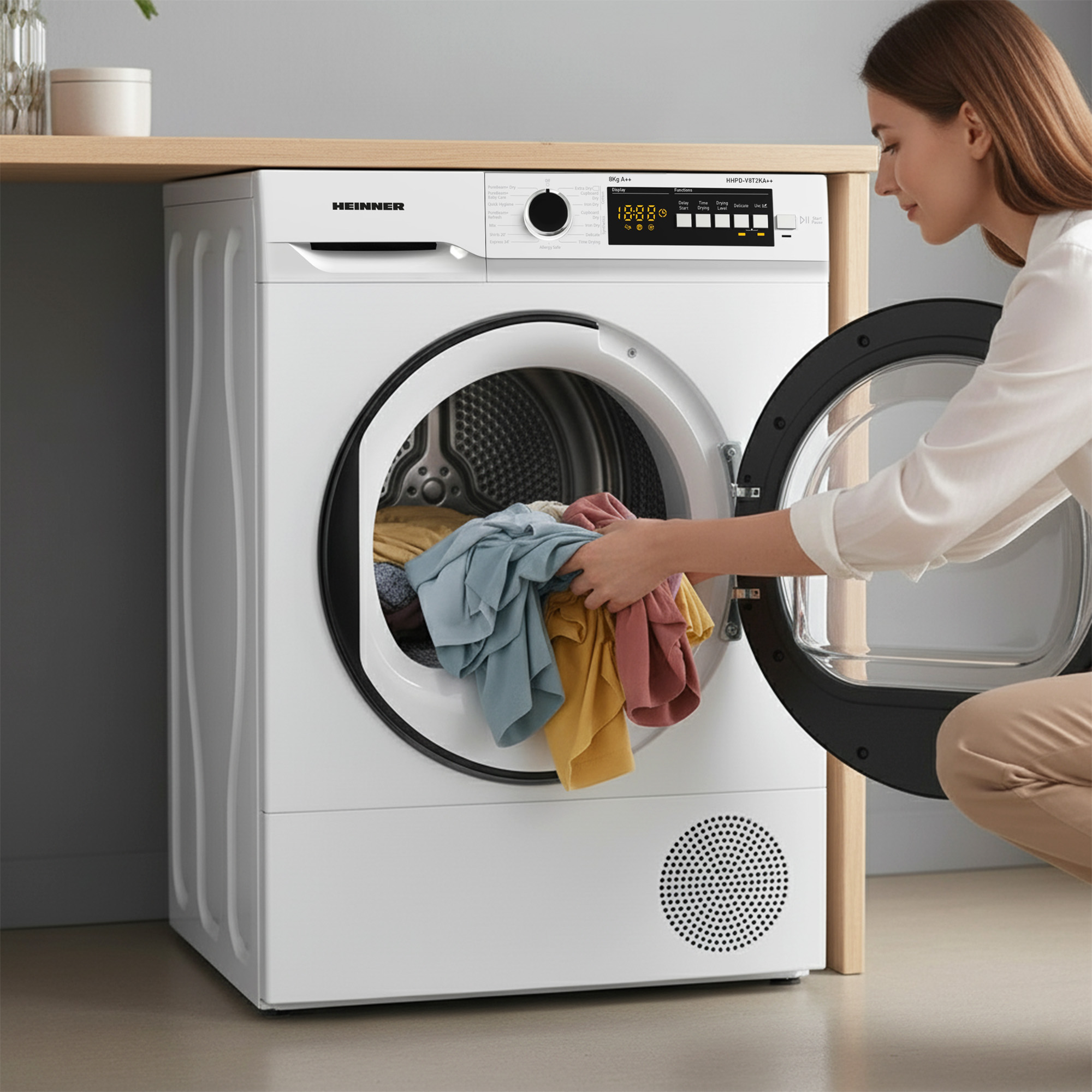 A woman putting clothes into a white dryer. The dryer is open, revealing colorful clothes inside. 