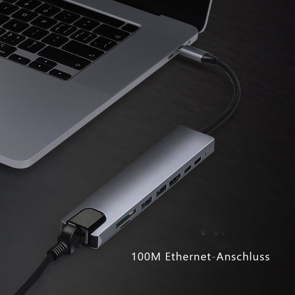 Ein Laptop ist mit einem silbernen Hub mit mehreren Anschlüssen verbunden. Ein schwarzes Kabel verbindet den Hub mit dem Laptop.