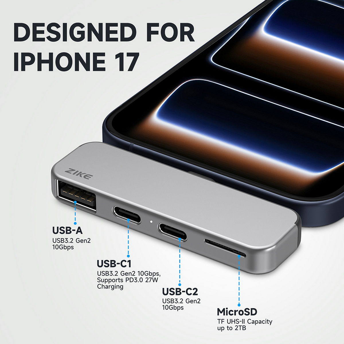 Ein silberner USB-Hub mit mehreren Anschlüssen, beschriftet mit USB-A, USB-C1, USB-C2 und MicroSD, wird neben einem iPhone gezeigt.
