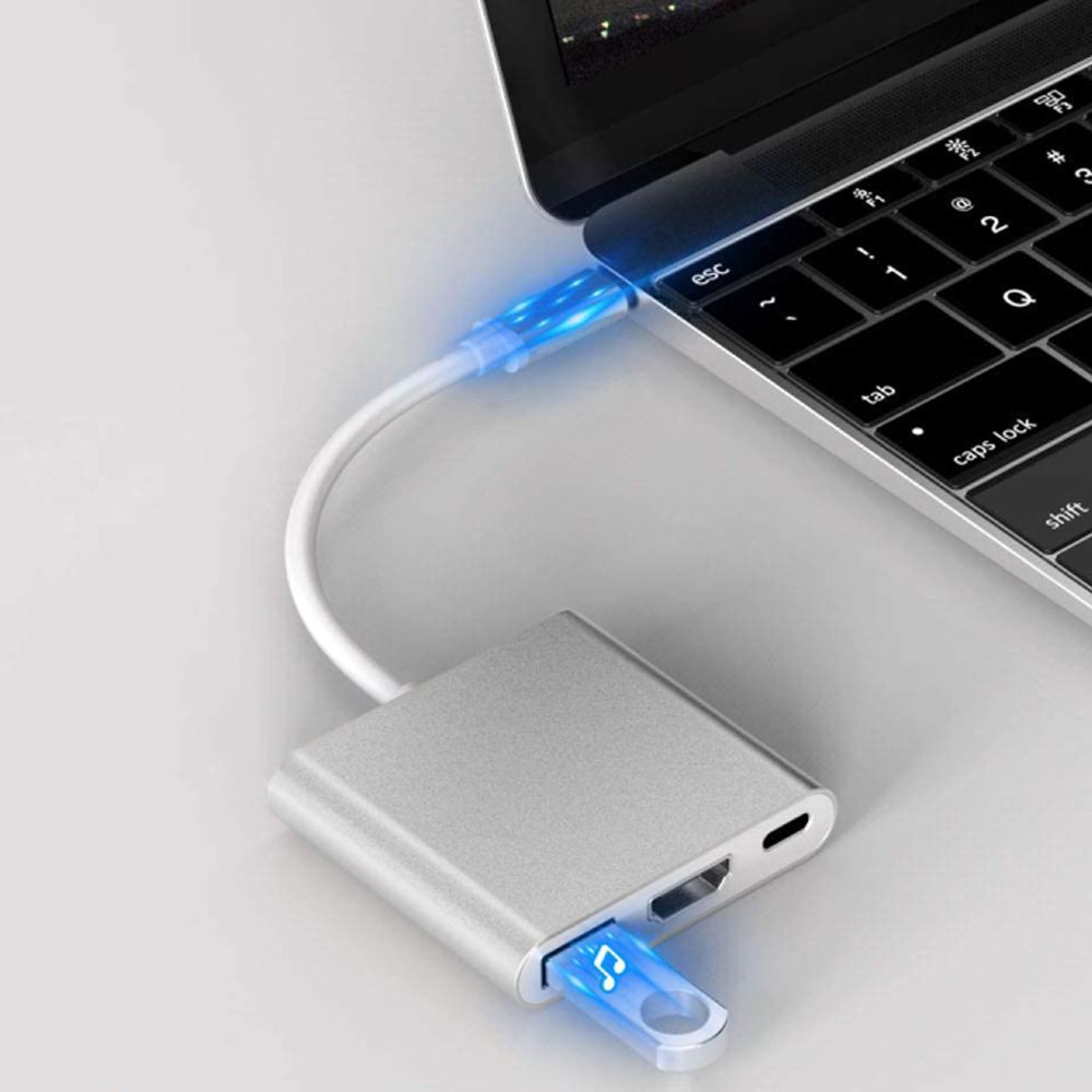 Ein Laptop mit einem silbernen USB-C-Adapter. Ein blau leuchtender USB-Stick ist in den Adapter gesteckt, was Datenübertragung anzeigt.