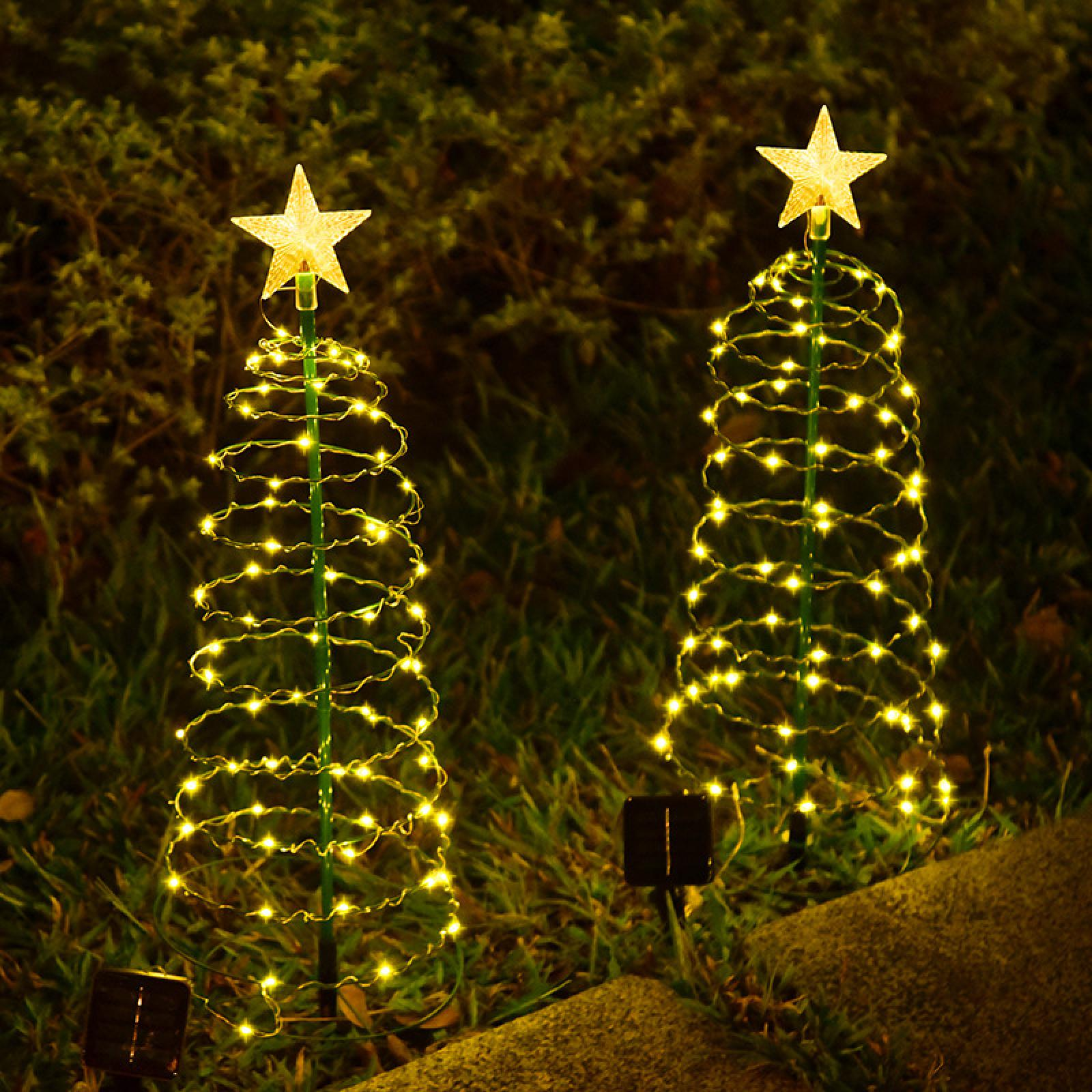 Zwei dekorative Weihnachtsbaumlichter. Jedes hat einen Stern oben und ist mit gelben Lichtern bedeckt. Sie stehen auf grünem Gras.