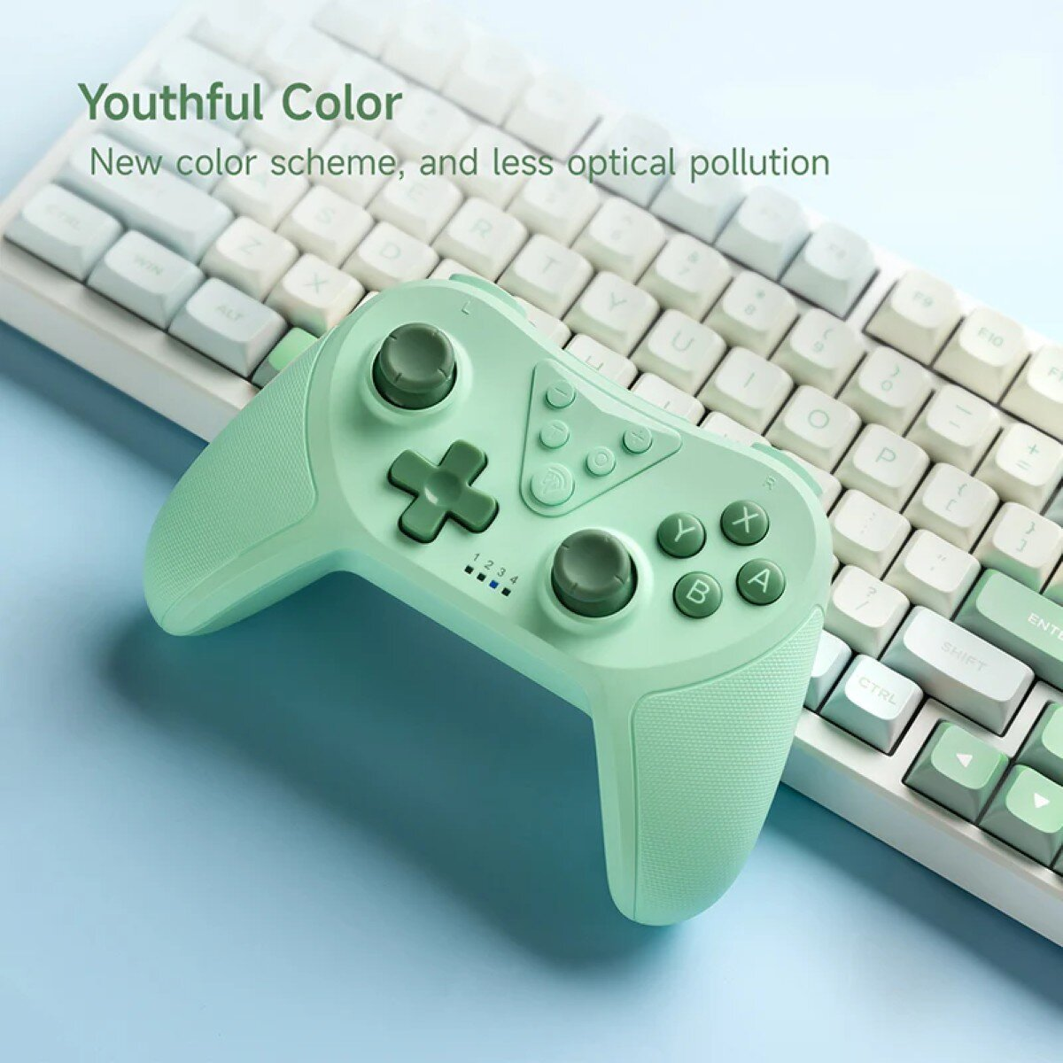 A mint-green gamepad rests on a blue surface, in front of a white keyboard. The gamepad has buttons and a D-pad. Text above says 'Youthful Color'.