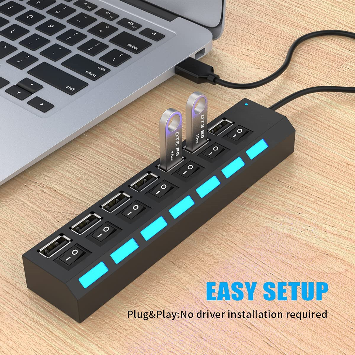 Ein Laptop ist mit einem schwarzen USB-Hub verbunden. Zwei USB-Laufwerke sind eingesteckt. Der Hub hat leuchtende blaue Lichter und Schalter.