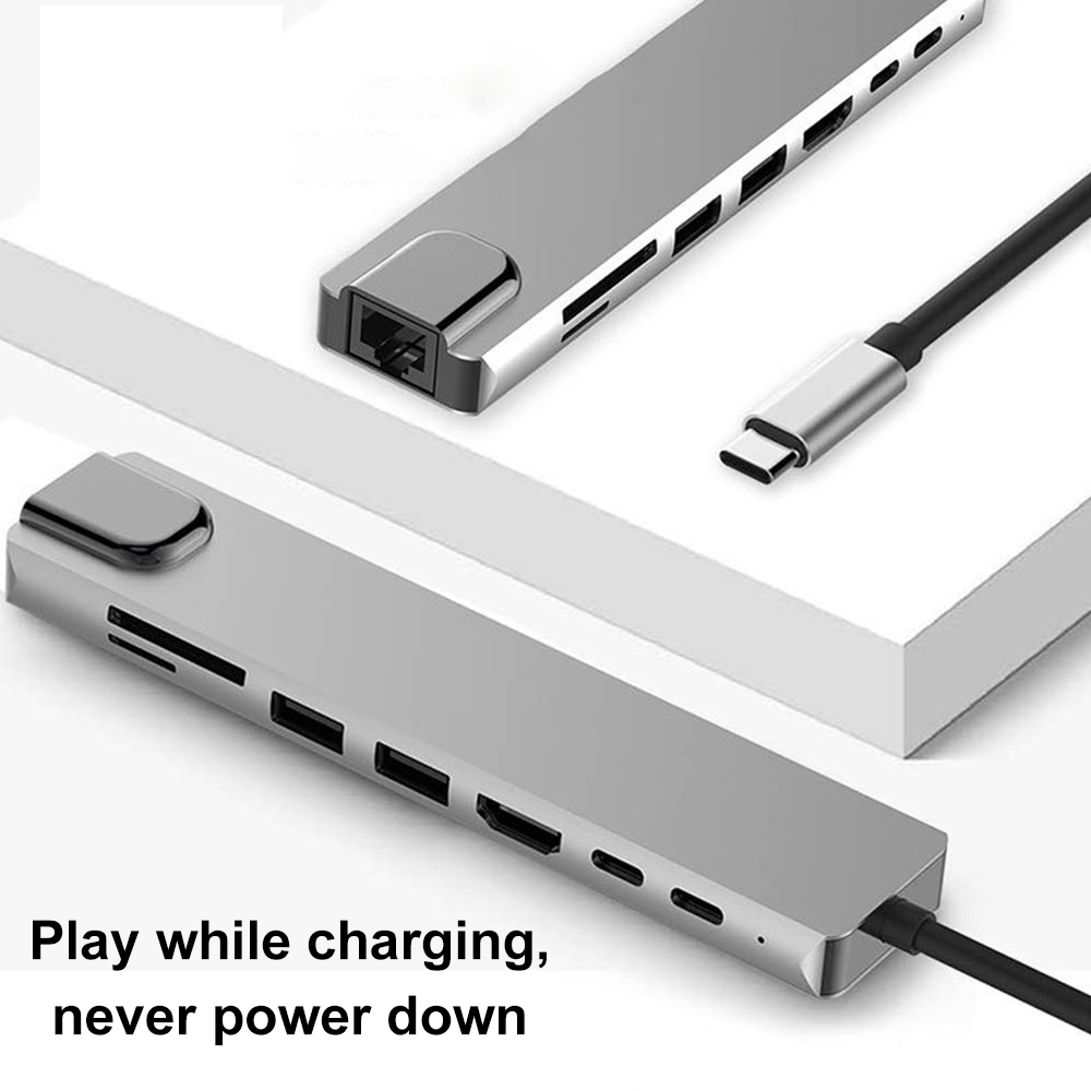 Silberner USB-C-Hub mit mehreren Anschlüssen und einem schwarzen Kabel. Text: Spielen beim Laden, nie herunterfahren.