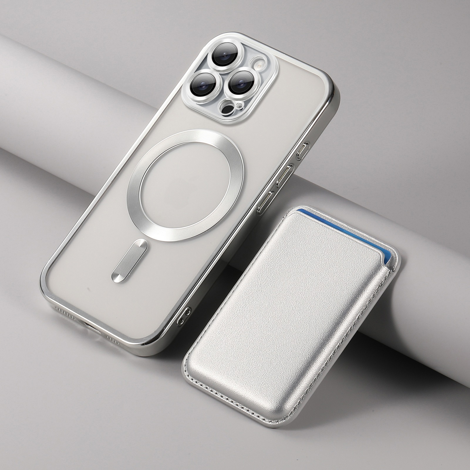 Una custodia per iPhone argentata e un piccolo portafoglio abbinato sono su una superficie bianca con una leggera angolazione.