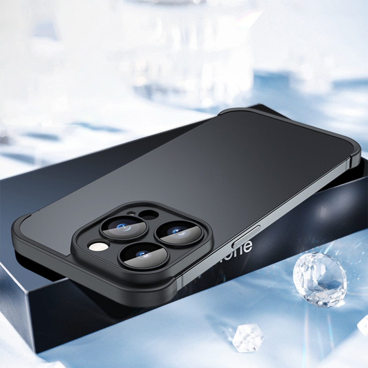 Una custodia nera per telefono con modulo fotocamera è posizionata su una scatola nera. Ci sono diamanti sullo sfondo su una superficie azzurra.