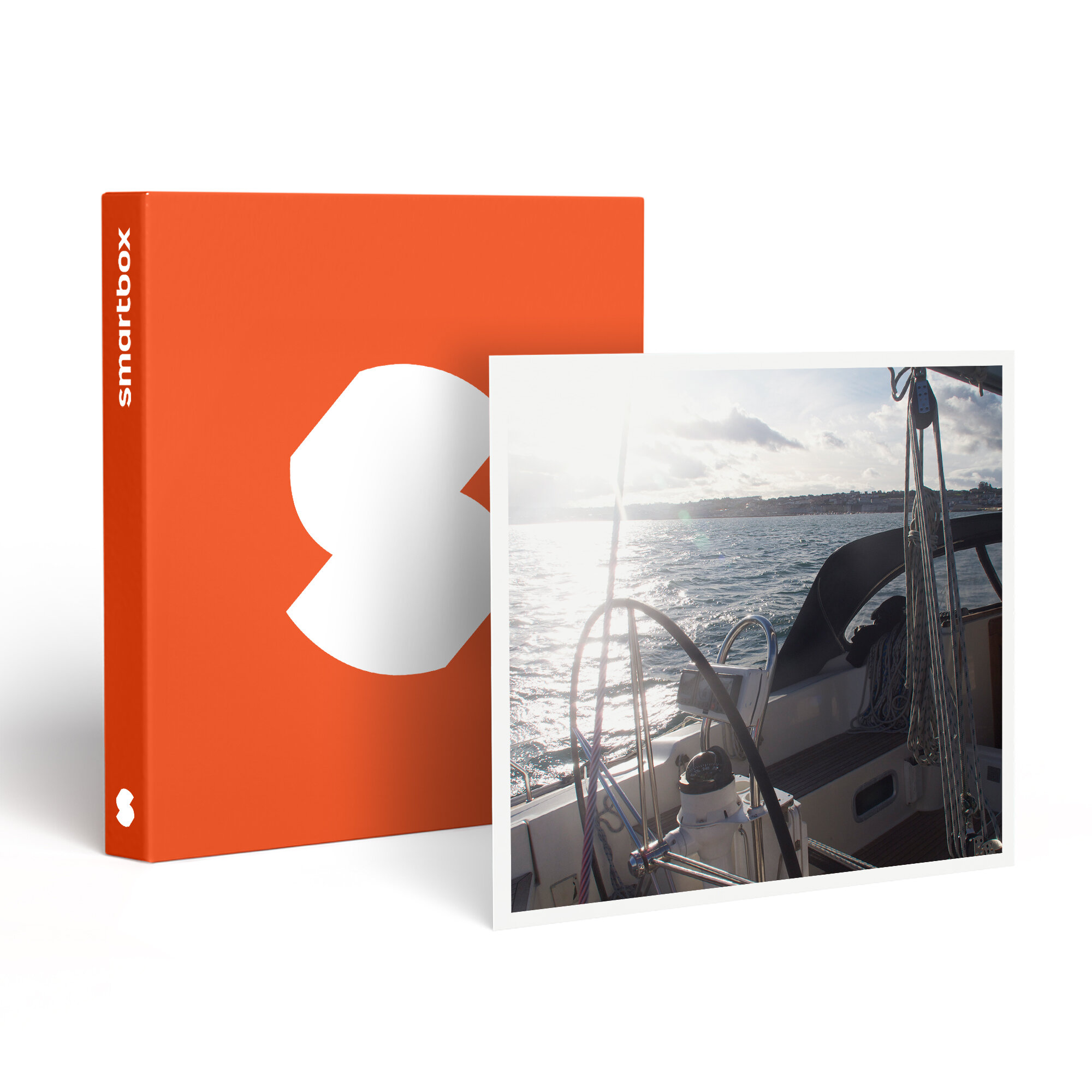 Cubierta de velero con timón y cuerdas, junto a una caja naranja con un logotipo blanco. Agua y cielo visibles.