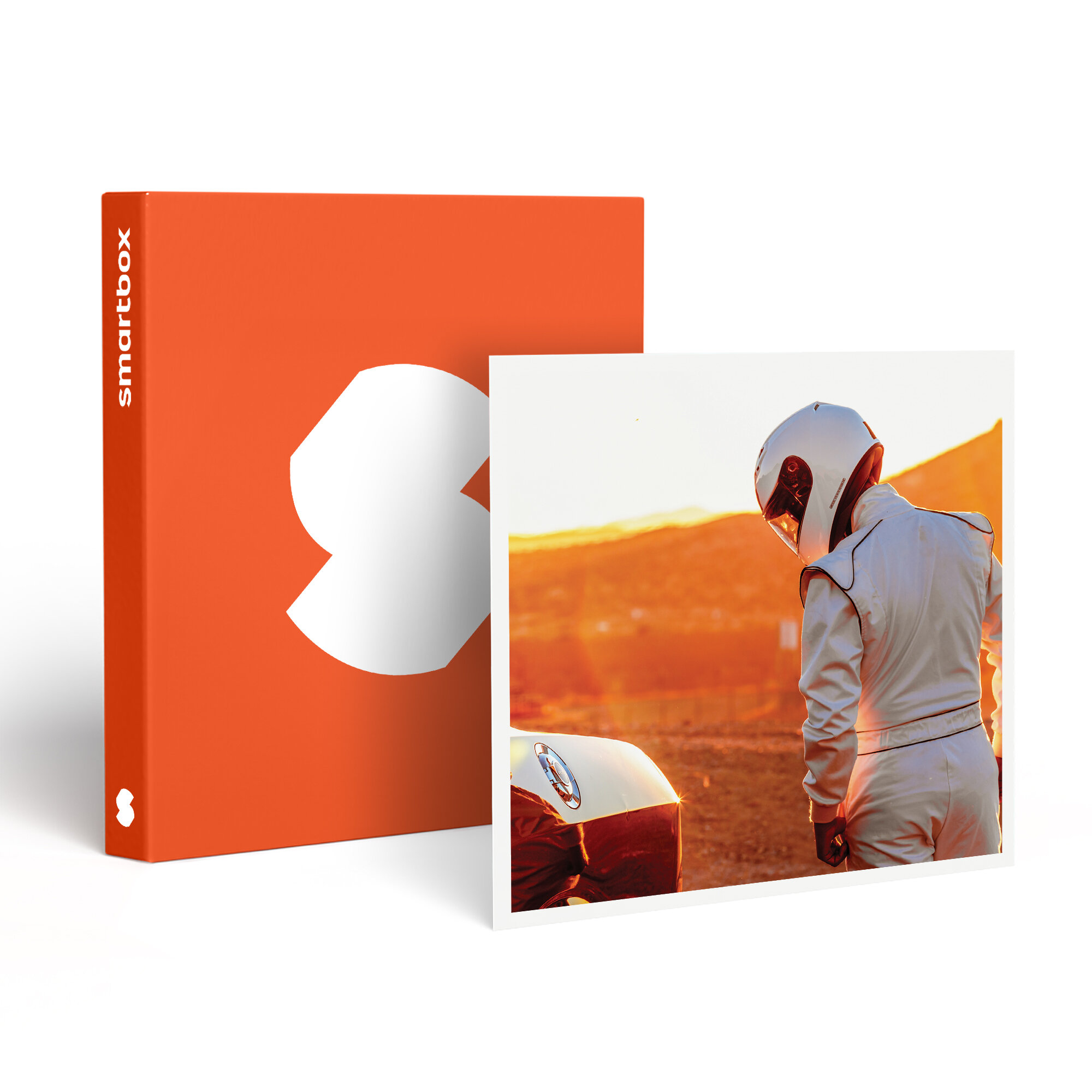 Una Smartbox naranja y una foto de un corredor con traje y casco blancos de pie cerca de un coche al atardecer.
