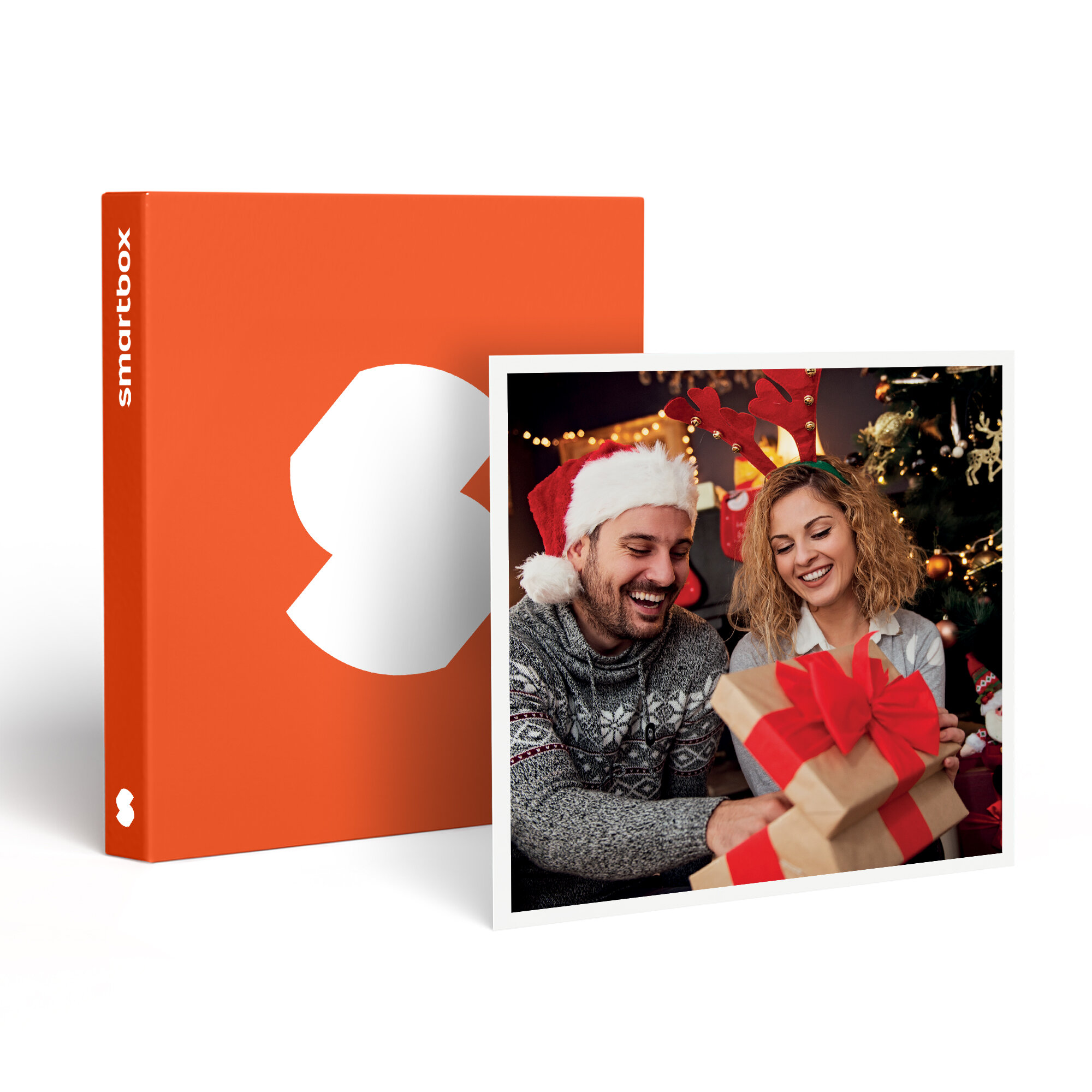 Una pareja sonríe abriendo regalos cerca de un árbol de Navidad. A la izquierda, una caja naranja con un logo blanco.