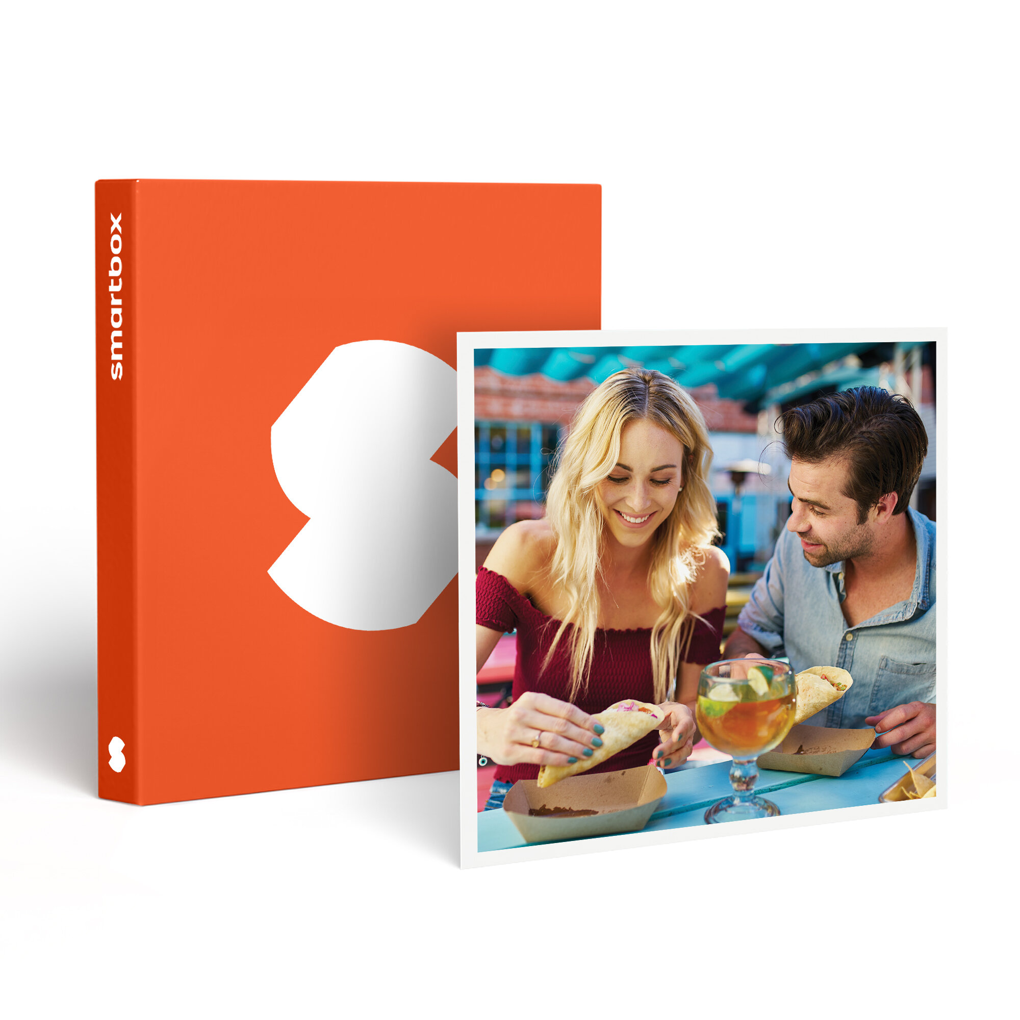 Una pareja come tacos, bebidas en la mesa. Una caja naranja con un logo blanco a la izquierda.