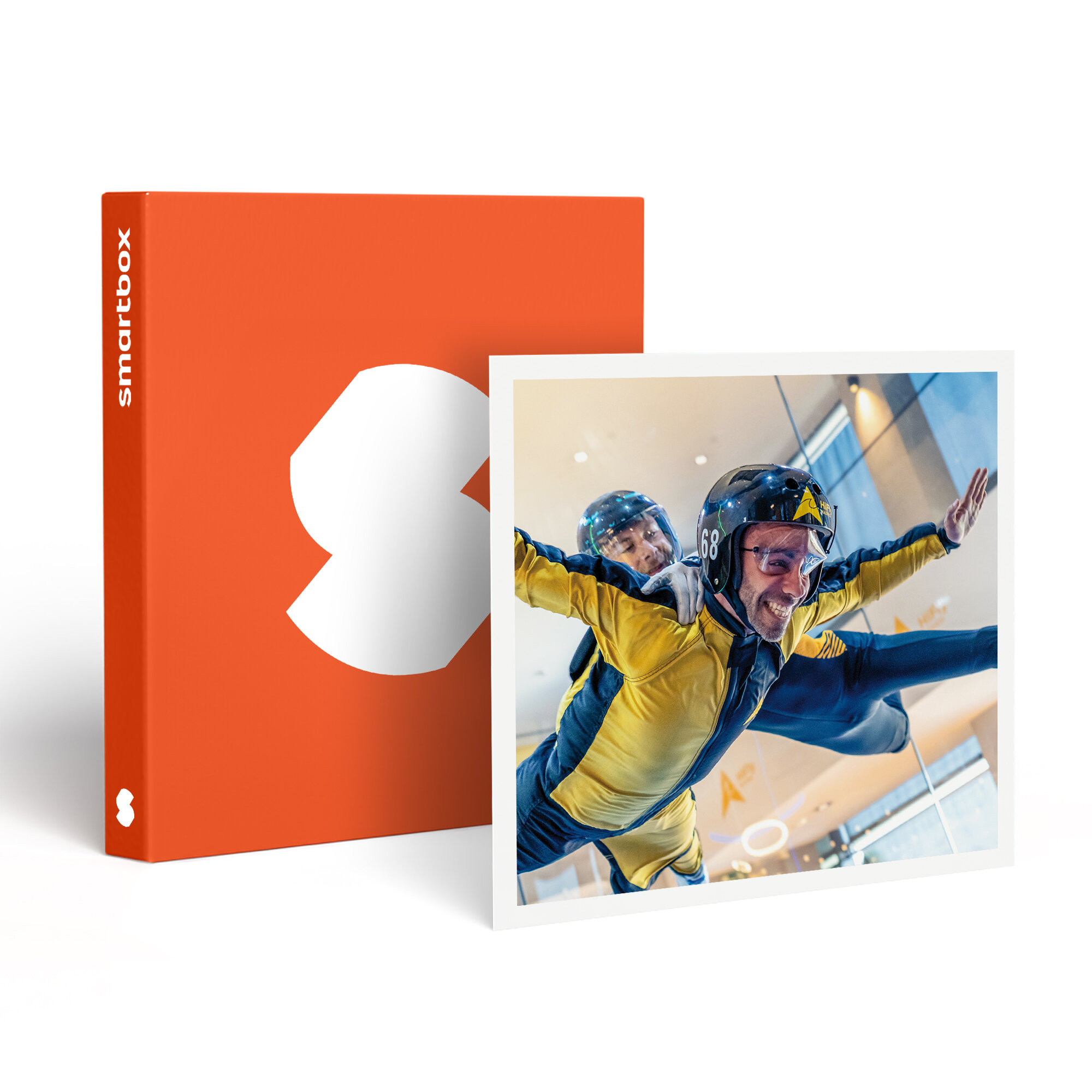 Dos personas con trajes y cascos amarillos vuelan en túnel de viento. Un producto Smartbox naranja a la izquierda.