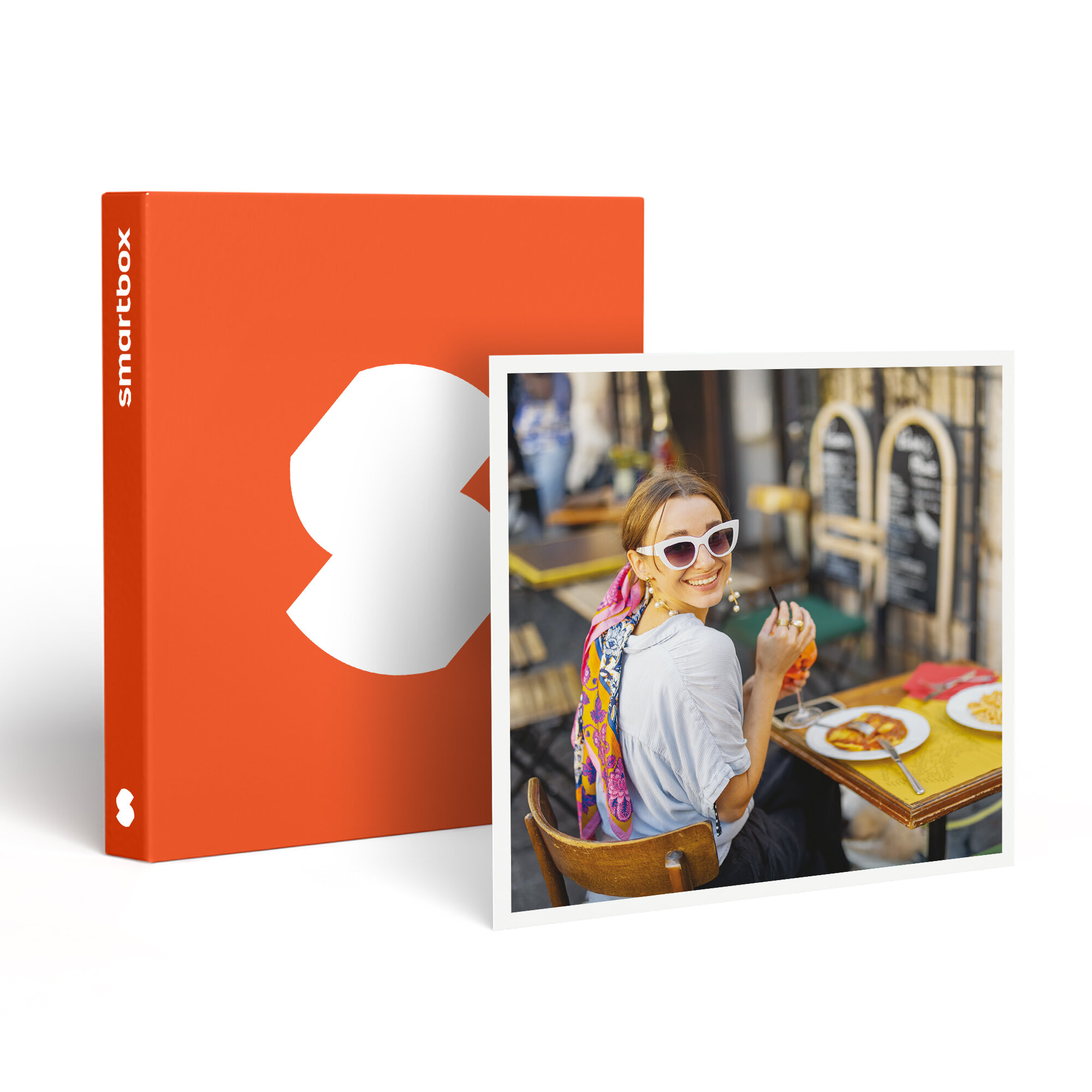 Mujer en un café, sonriendo, sosteniendo una bebida. Caja naranja con logo blanco. Comida en mesa amarilla.