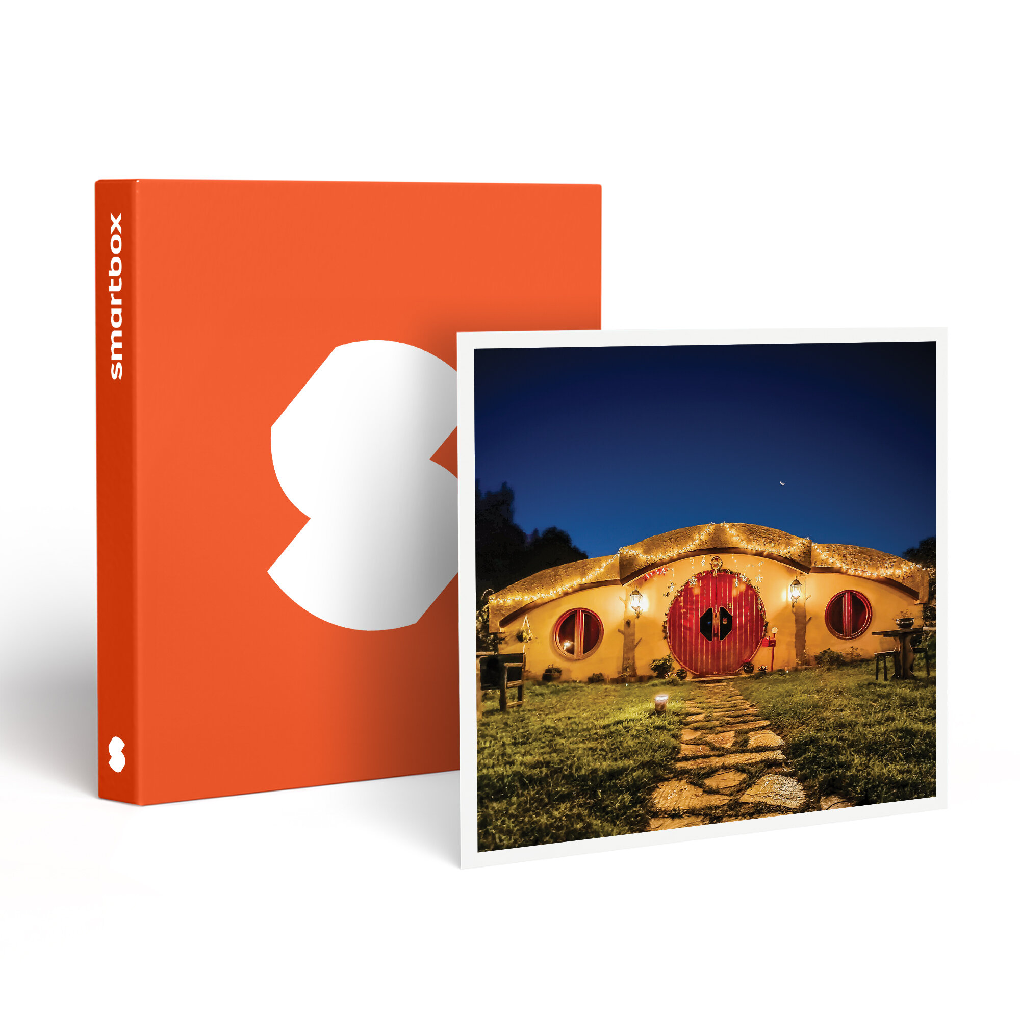 La imagen muestra una casa de Hobbit por la noche, junto a una caja naranja con un logotipo blanco. La casa tiene una puerta roja.