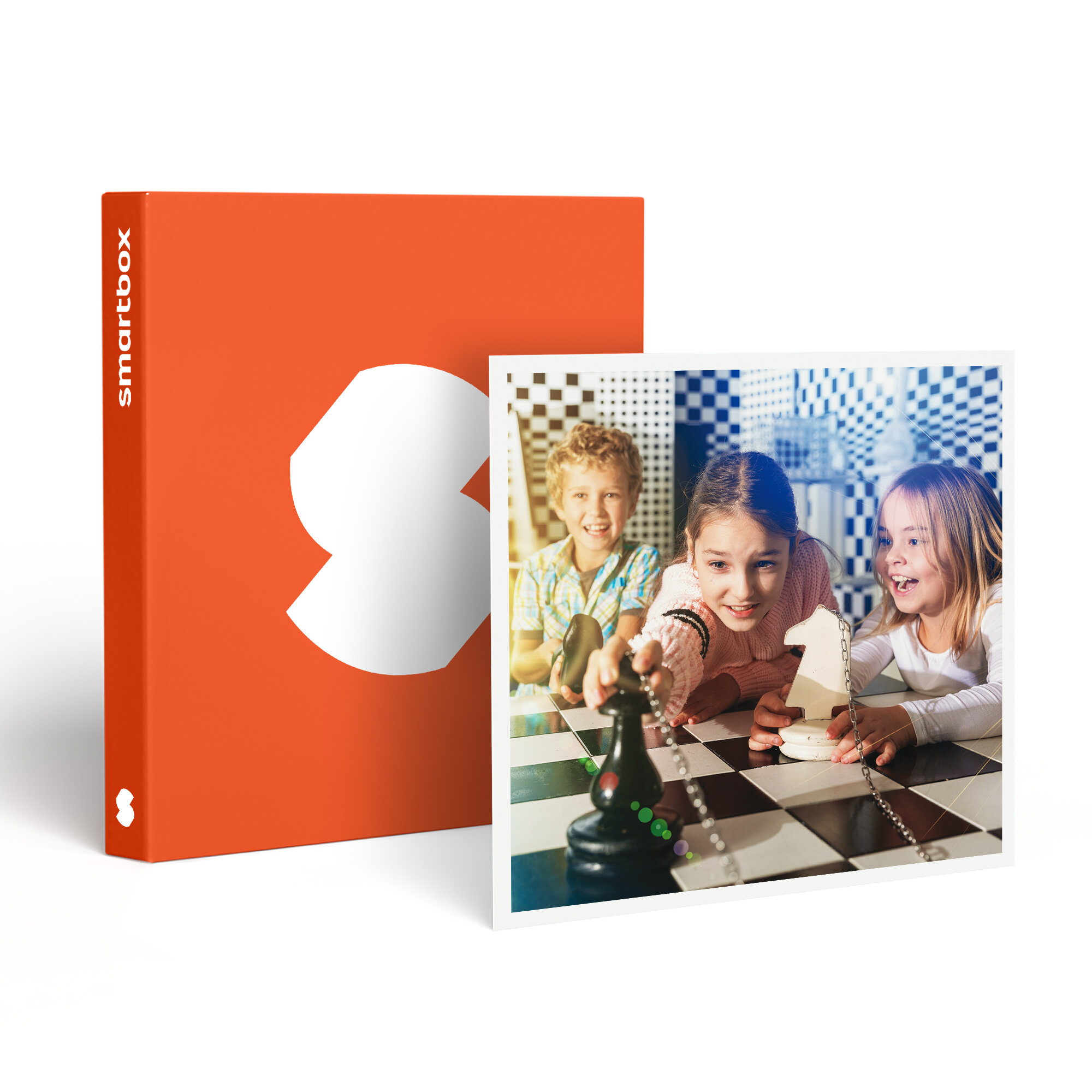 Tres niños juegan al ajedrez. A la izquierda, una caja naranja con un logotipo blanco.