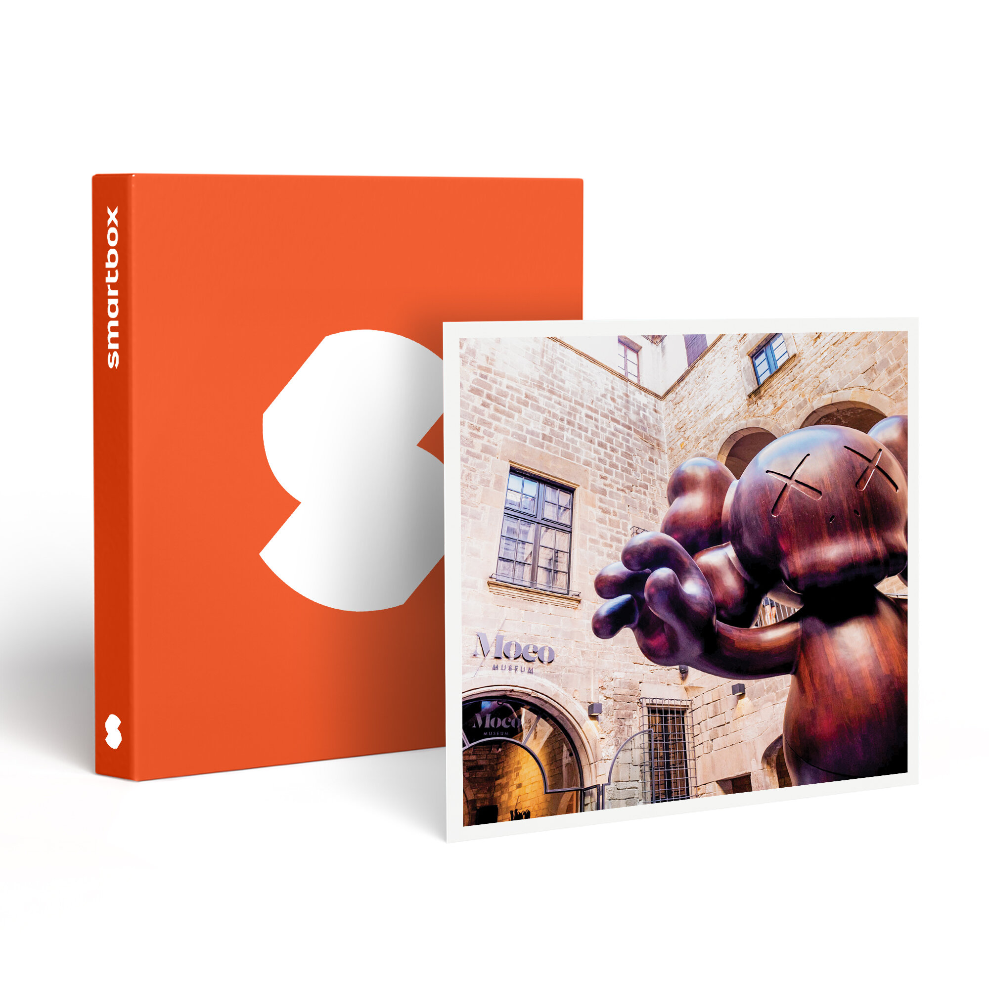 Una caja naranja con un diseño blanco se encuentra junto a una foto enmarcada de una escultura KAWS frente al Museo MoCo.