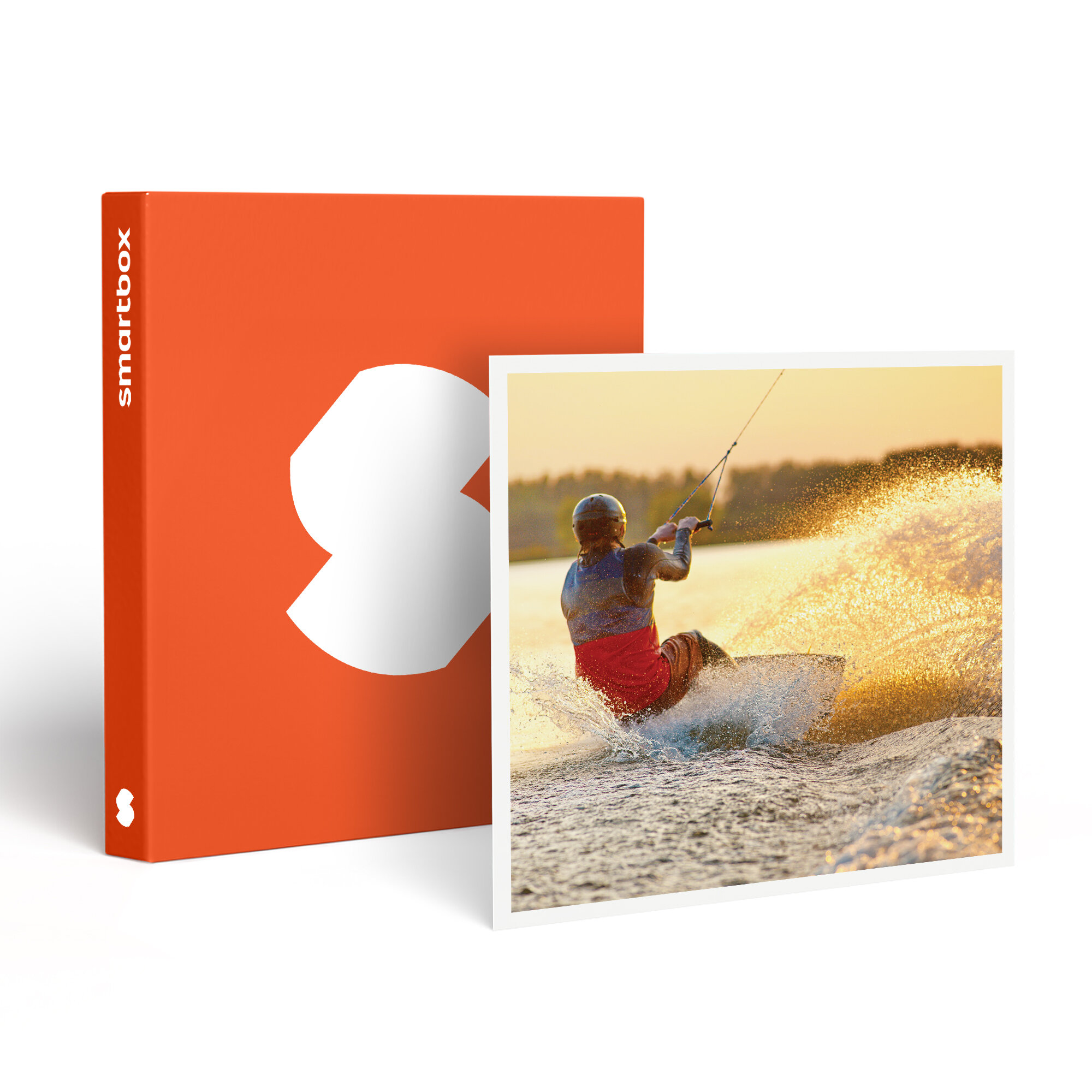 Un wakeboarder en el agua, caja naranja con logo blanco. El agua salpica brillantemente, fondo de puesta de sol.