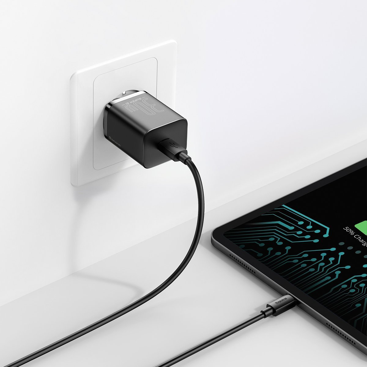 Ein schwarzes Ladegerät ist in eine weiße Steckdose gesteckt. Ein Kabel verbindet sich mit einem Tablet, das 50 % Ladung anzeigt.