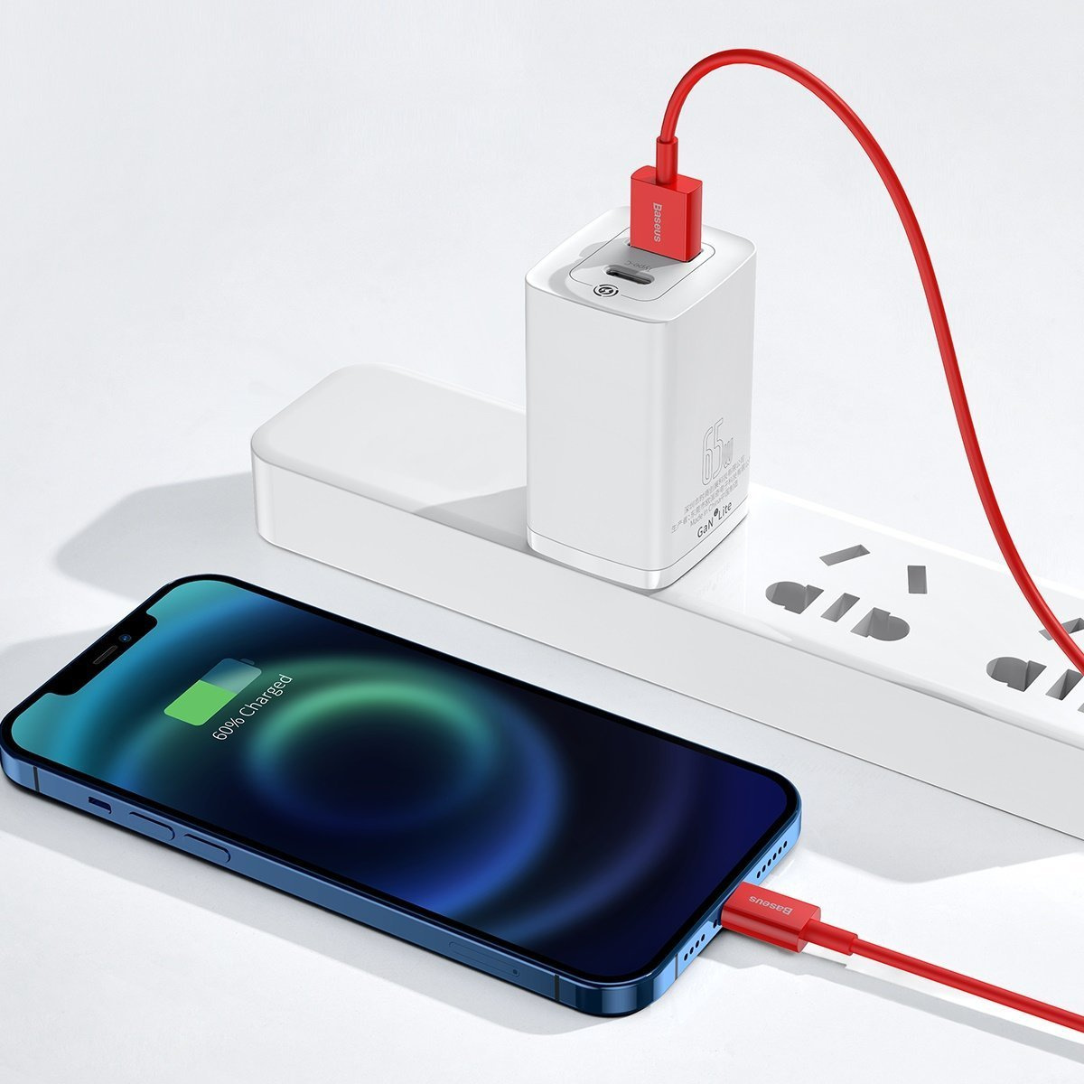 Een blauwe iPhone wordt opgeladen met een rode kabel. Een witte oplader is aangesloten op een stopcontact. De telefoon toont 60% opgeladen.
