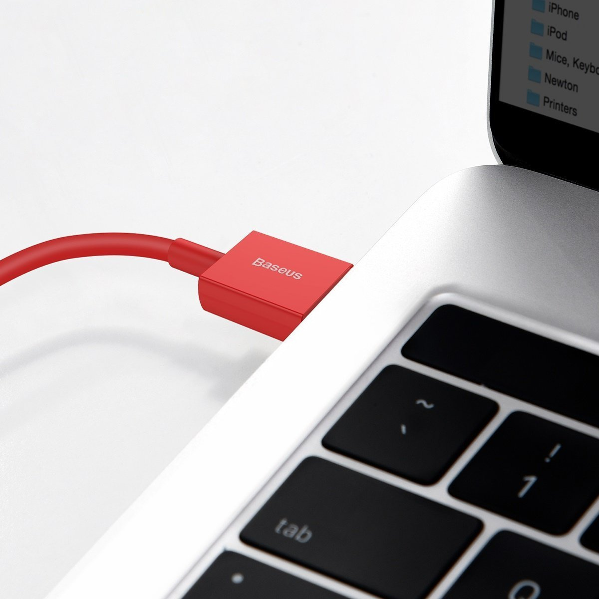 Een rode Baseus USB-C-kabel is aangesloten op een zilveren laptop. Het toetsenbord en een scherm met bestandsnamen zijn zichtbaar.