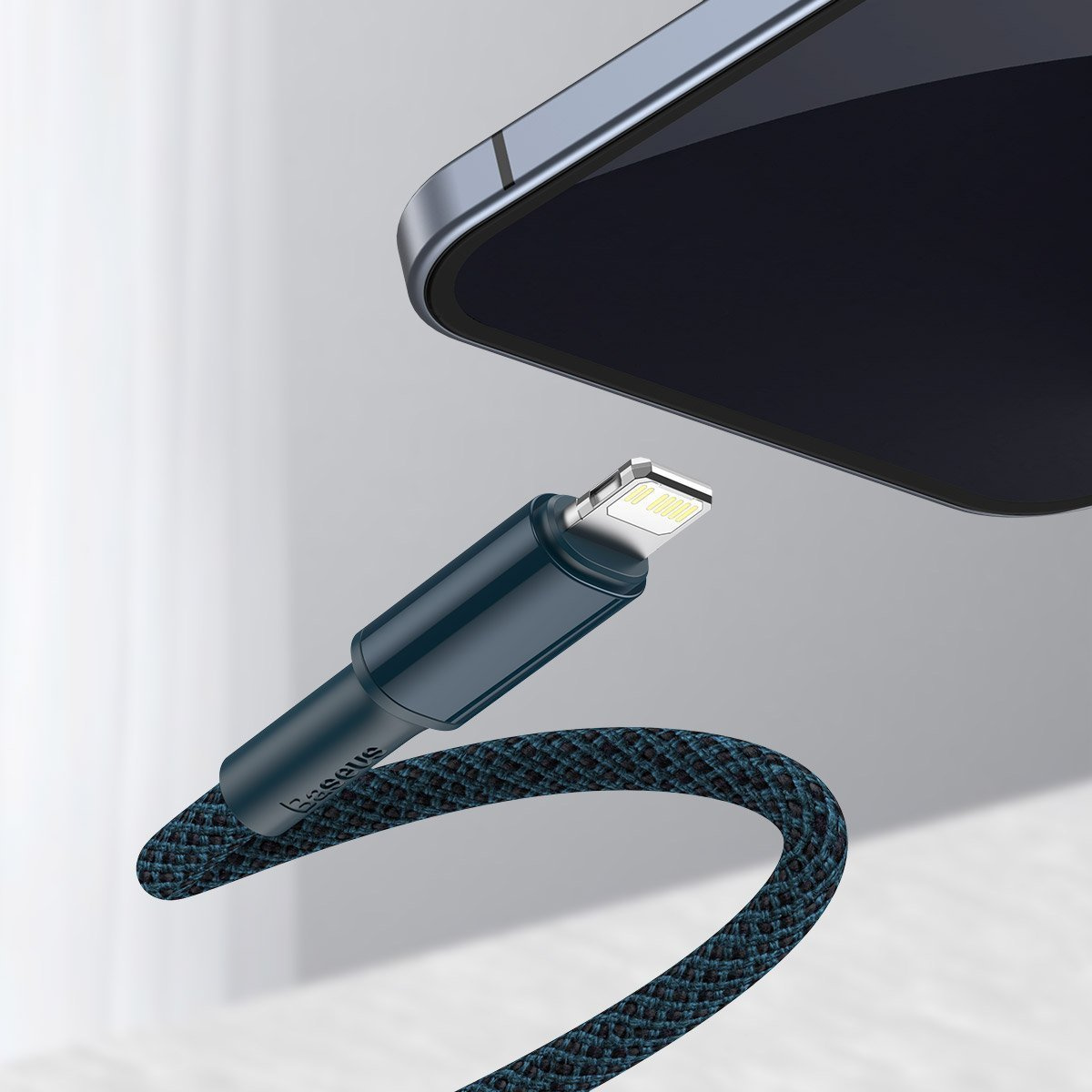 Un câble de charge bleu foncé est connecté à un téléphone. Le câble a une texture tissée et la marque 'Baseus' est visible.