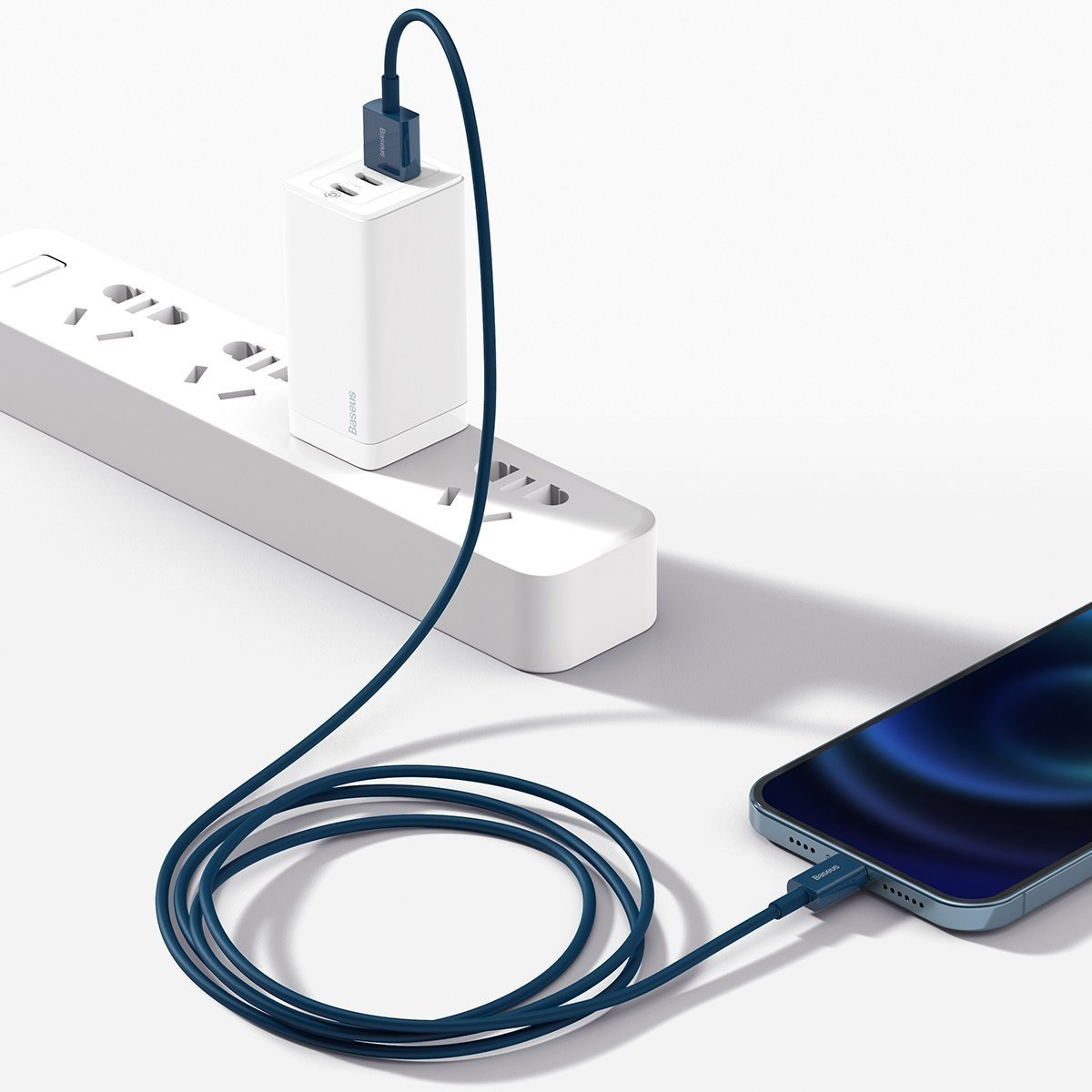 Un telefono in carica. Una ciabatta e un caricabatterie bianchi sono collegati tramite un cavo blu a un telefono.