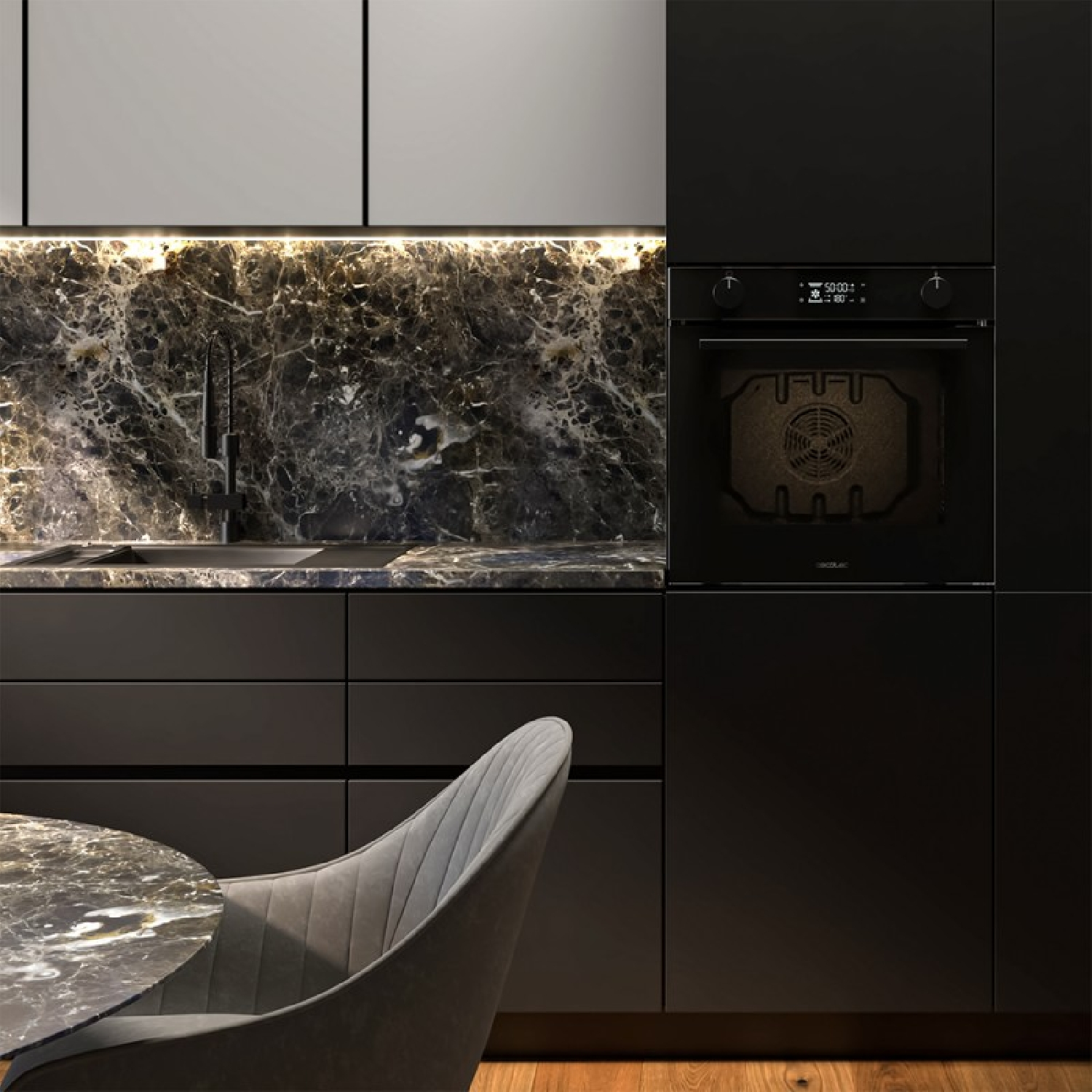 Cocina moderna con gabinetes negros, encimera de mármol, horno y una mesa de comedor con silla gris.