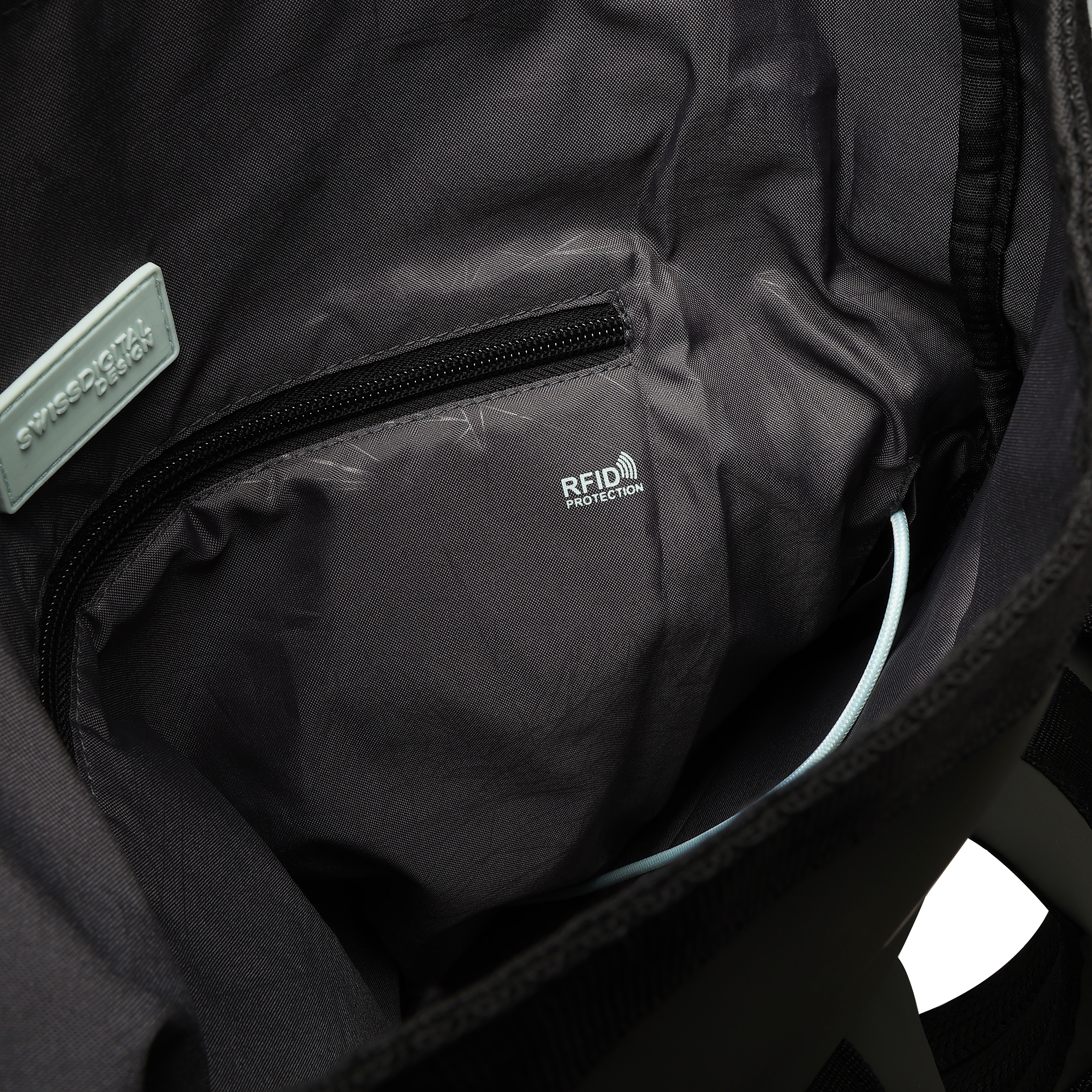 Vista interna di una borsa nera. Include una cerniera, un'etichetta RFID e un cordino azzurro. Un'etichetta dice 'SWISS DIGITAL DESIGN'.