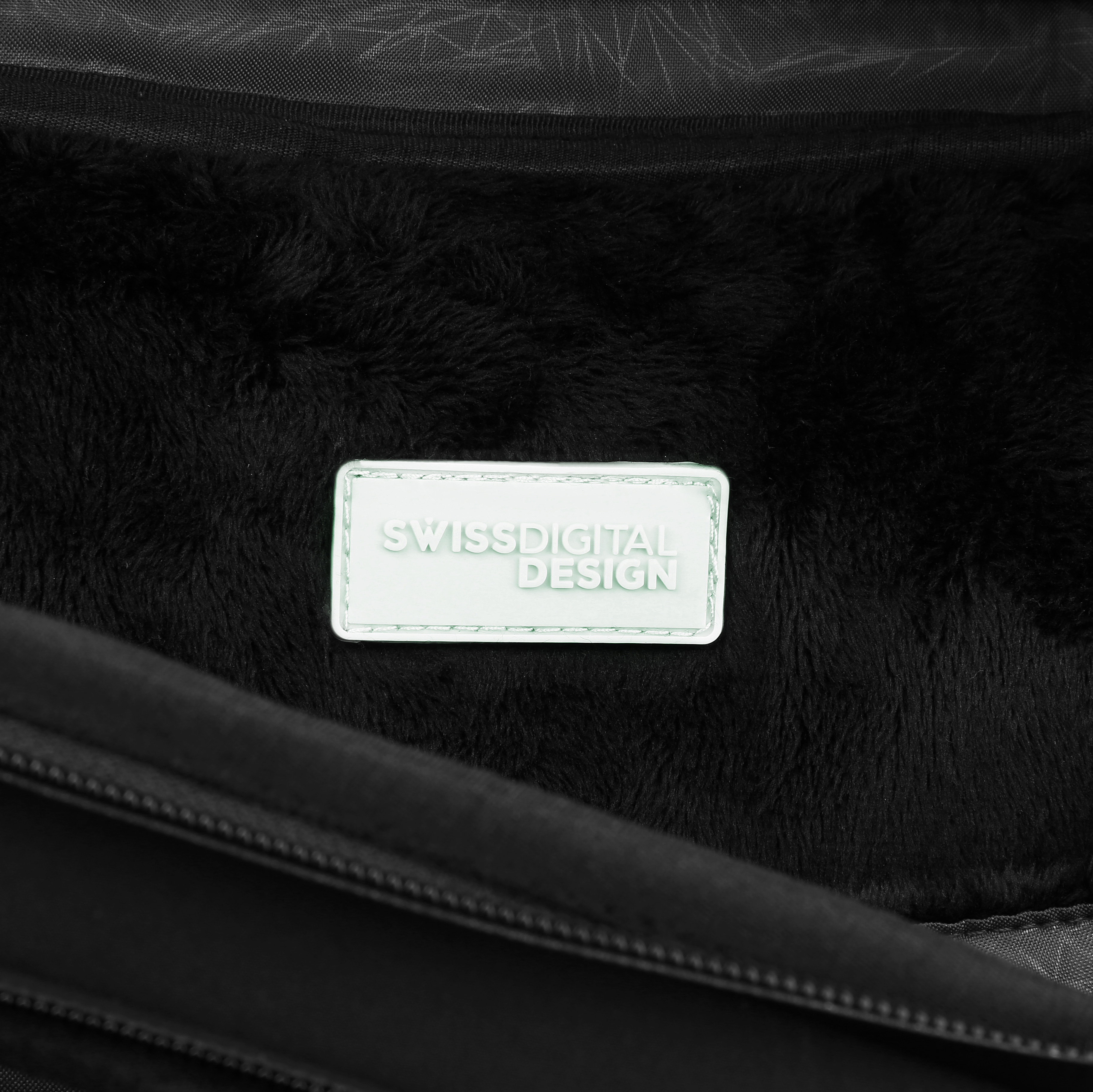 Primo piano dell'interno di una borsa con fodera nera e un'etichetta bianca con scritto 'SWISSDIGITAL DESIGN'.
