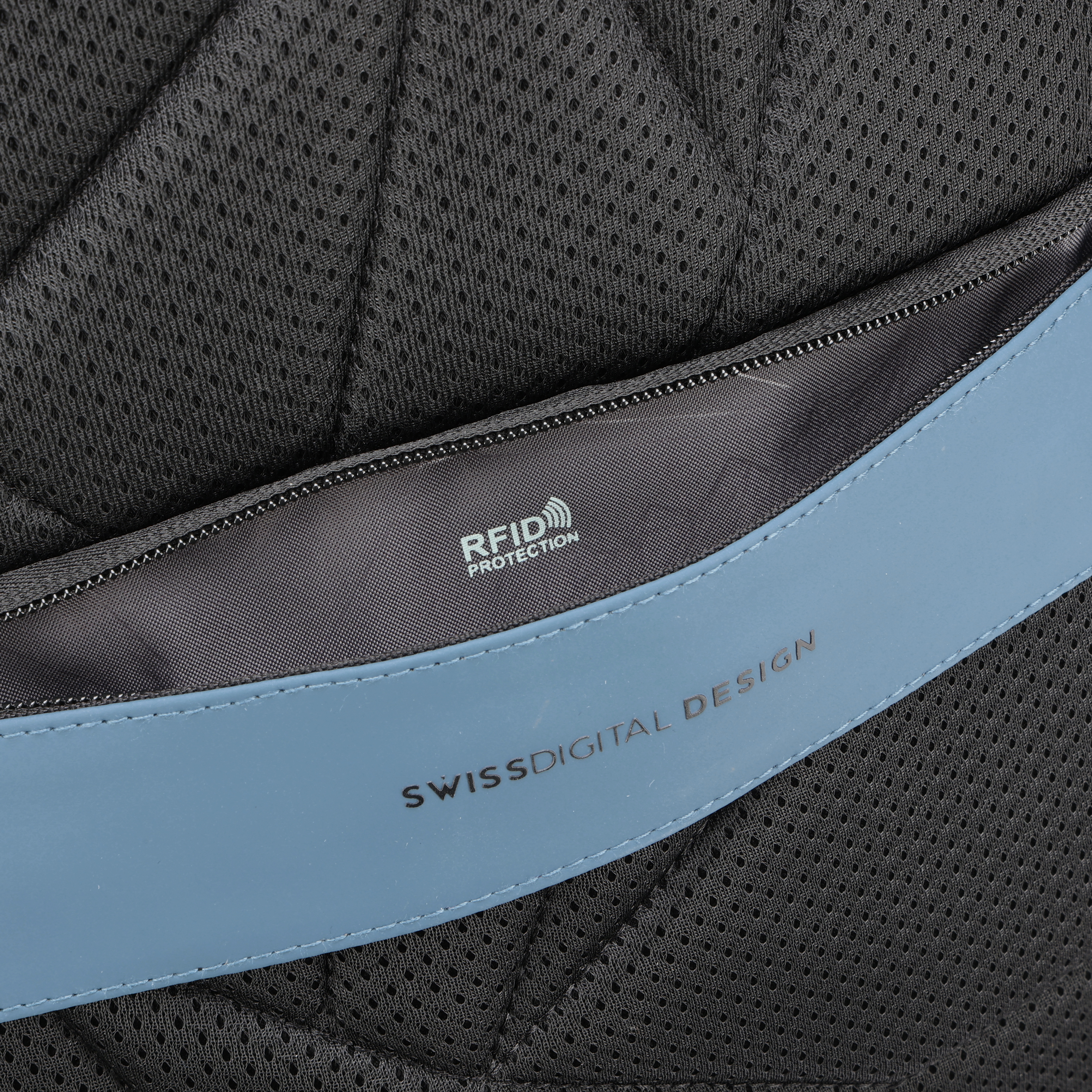 Primo piano del materiale dello zaino. Rete nera e cinturino blu con testo 'SWISS DIGITAL DESIGN' e 'RFID PROTECTION'.