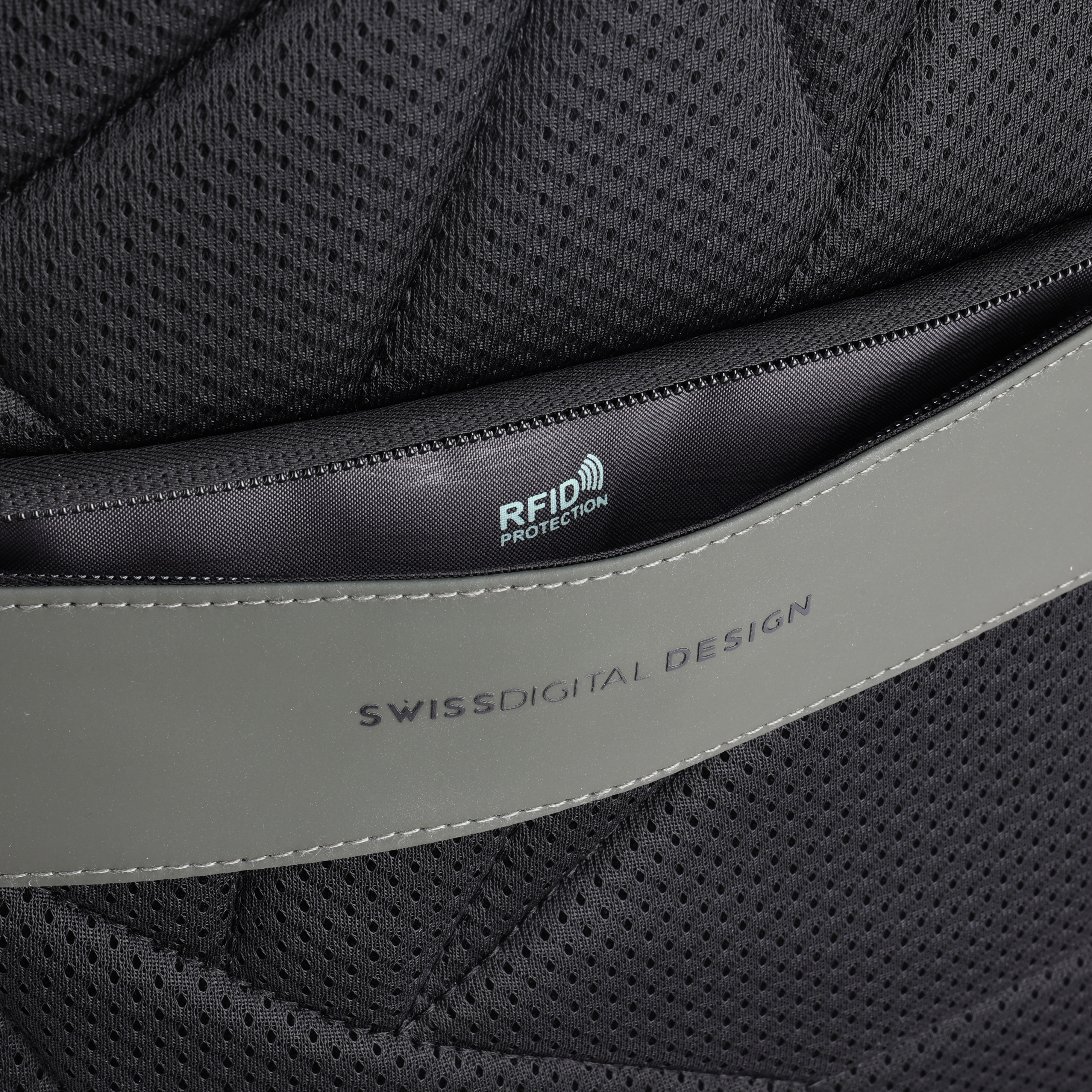 Primo piano del materiale dello zaino. Rete nera e cinturino grigio con 'SWISSDIGITAL DESIGN' e 'RFID PROTECTION'.