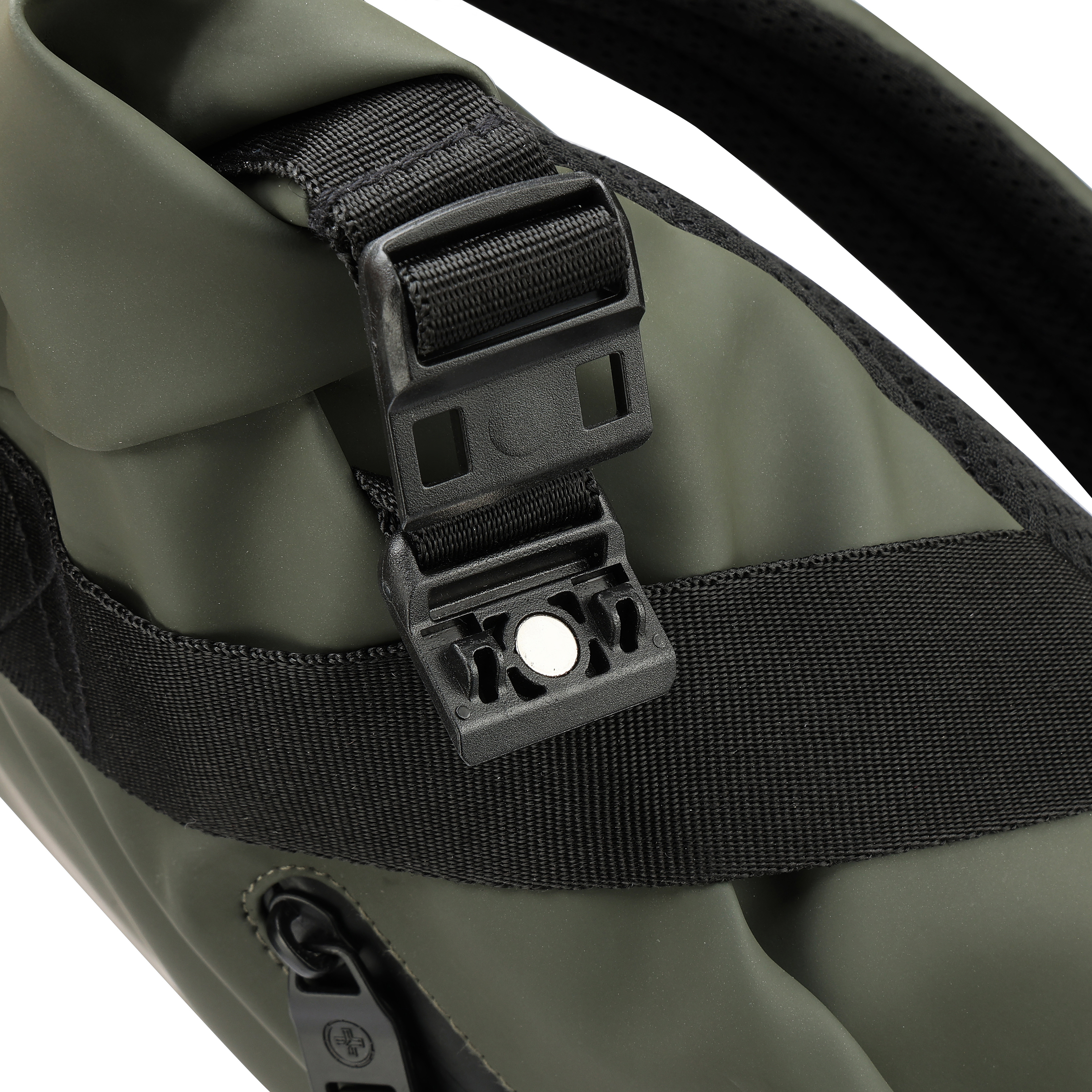 Primo piano di una chiusura nera su una borsa verde. La chiusura è attaccata a un cinturino nero. Sfondo bianco.