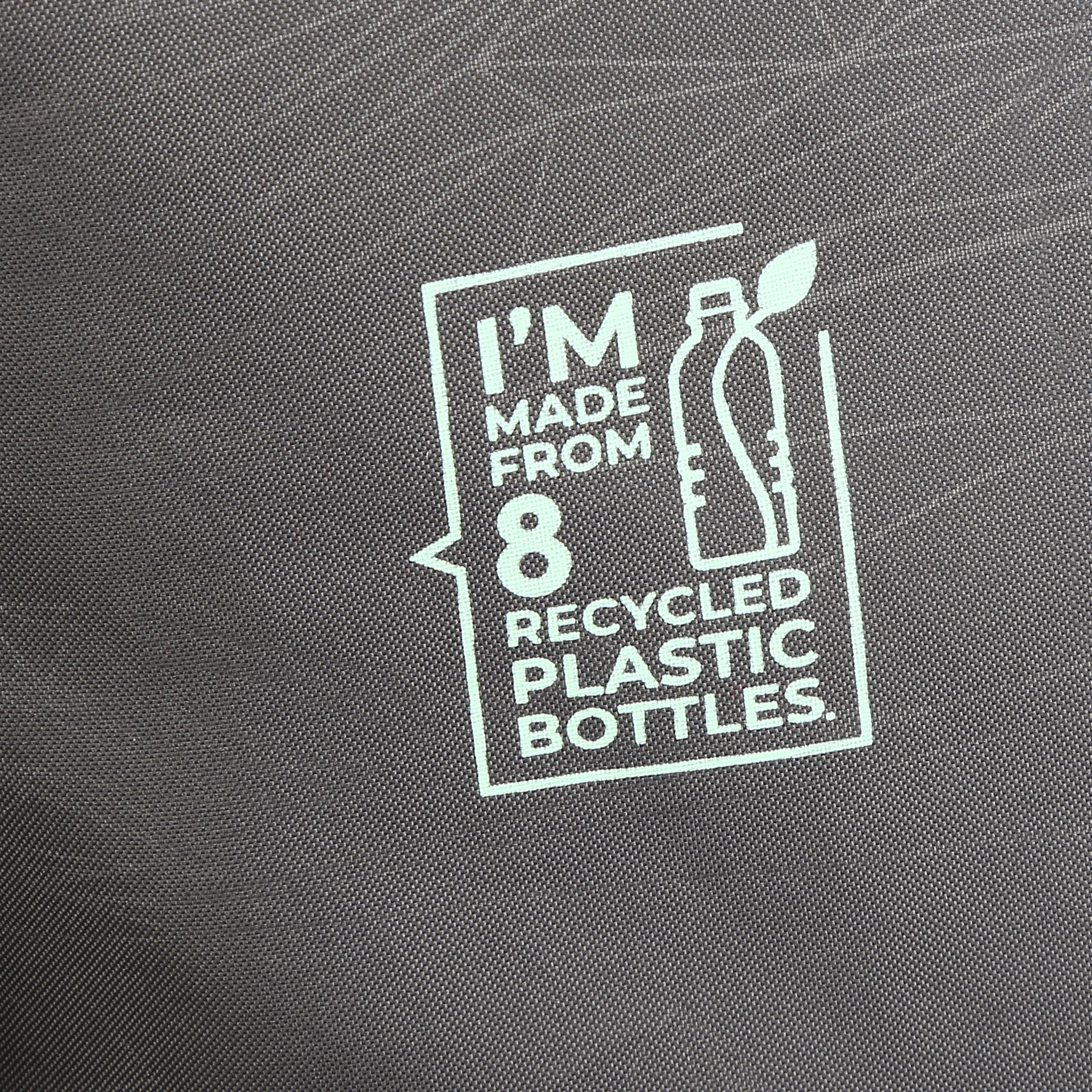 Primo piano di un cartello su tessuto grigio: "I'M MADE FROM 8 RECYCLED PLASTIC BOTTLES" con grafica di bottiglia.