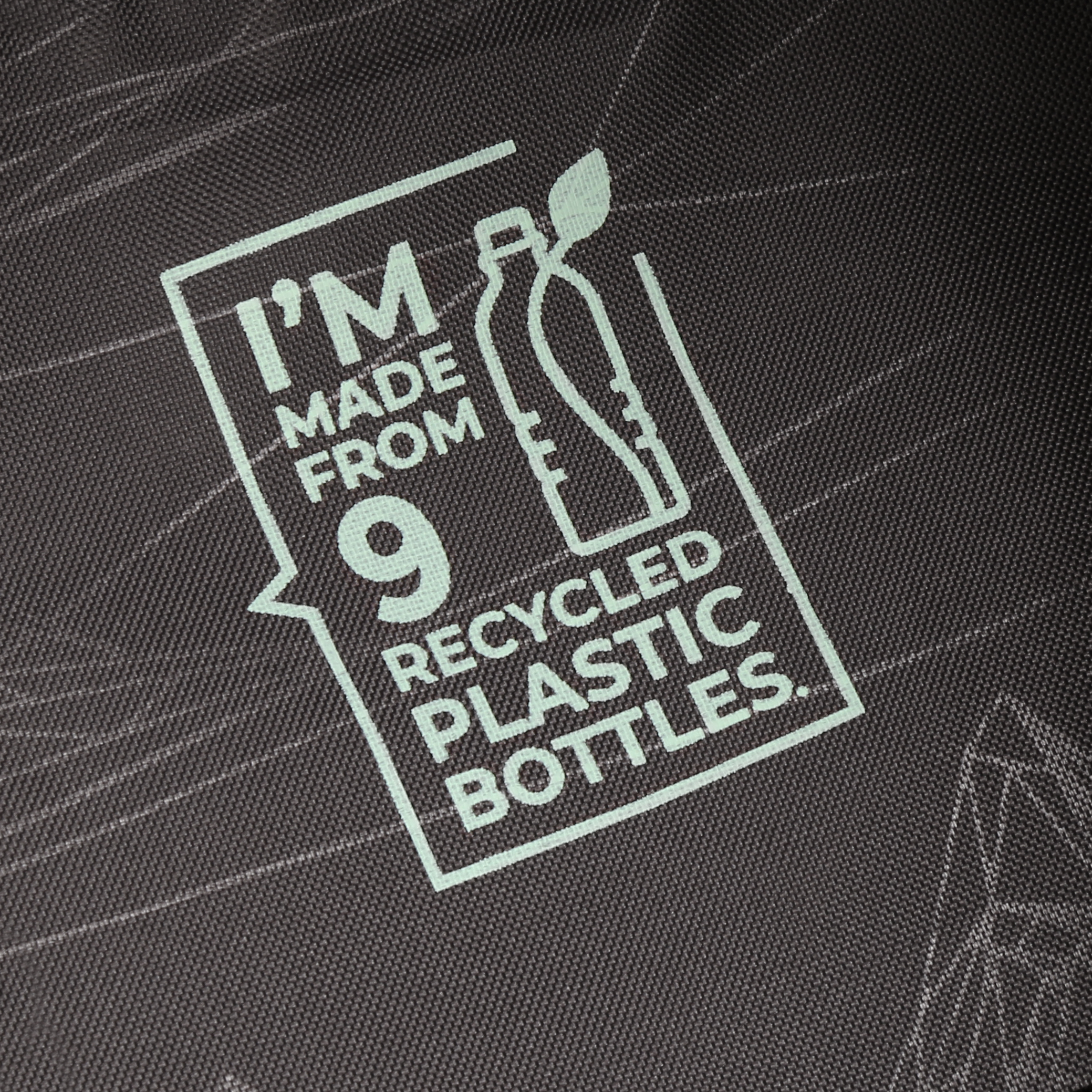Un'etichetta su tessuto recita 'I'M MADE FROM 9 RECYCLED PLASTIC BOTTLES' con un grafico di bottiglia.