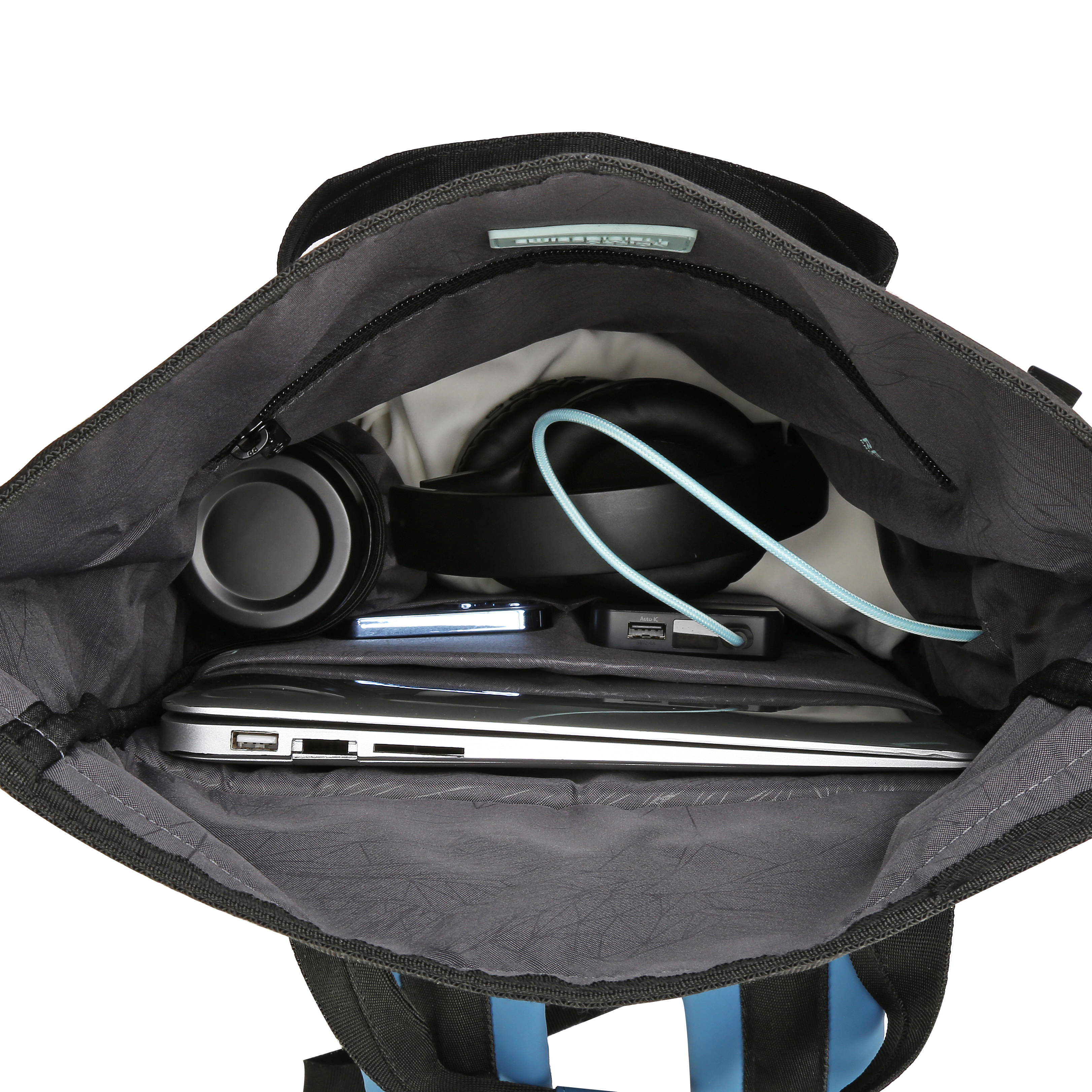 Zaino nero aperto con laptop, cuffie, telefono e caricabatterie all'interno. Cinghia blu e sfondo bianco.