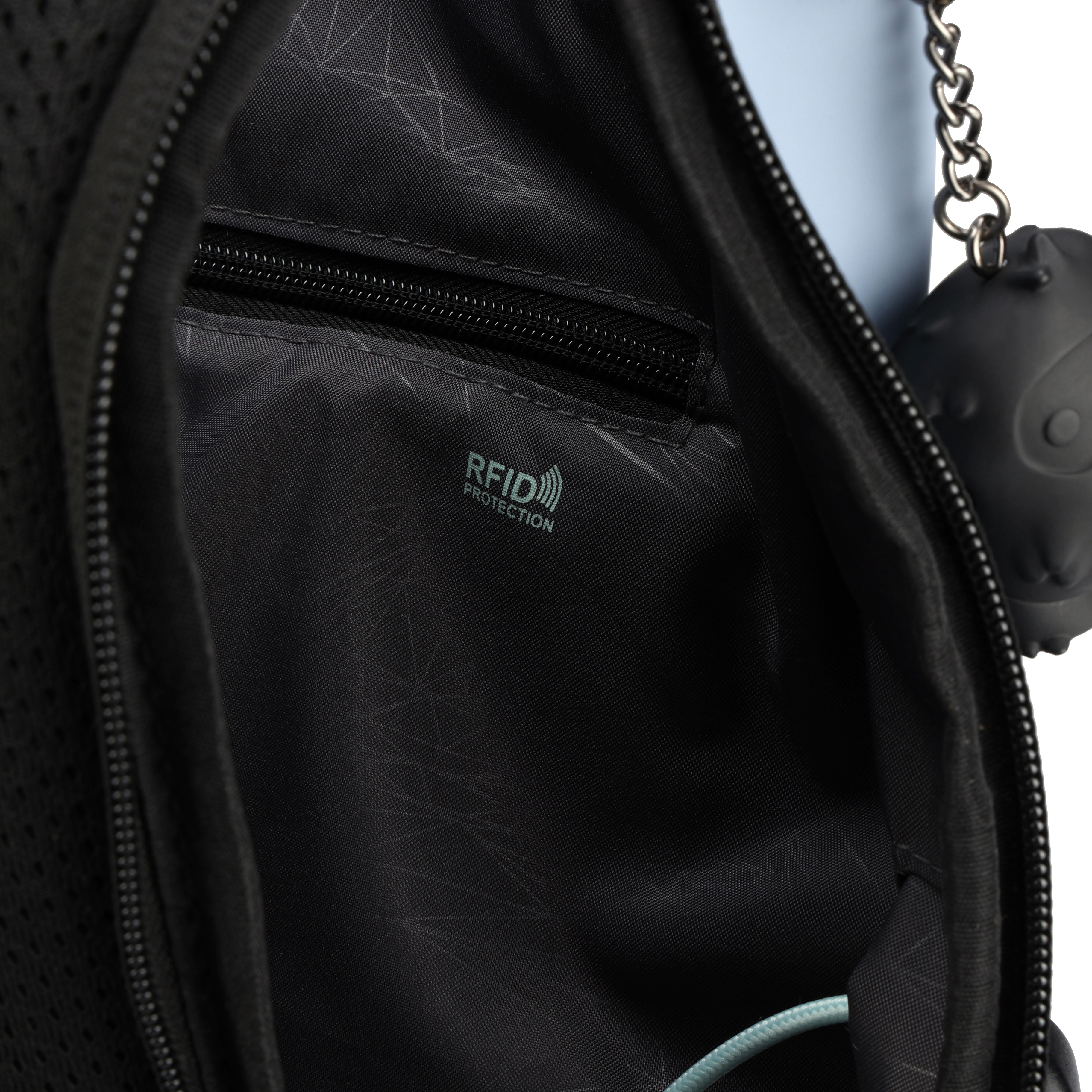 Primo piano dell'interno di una borsa nera con cerniera, etichetta di protezione RFID. Un portachiavi nero è appeso di lato.