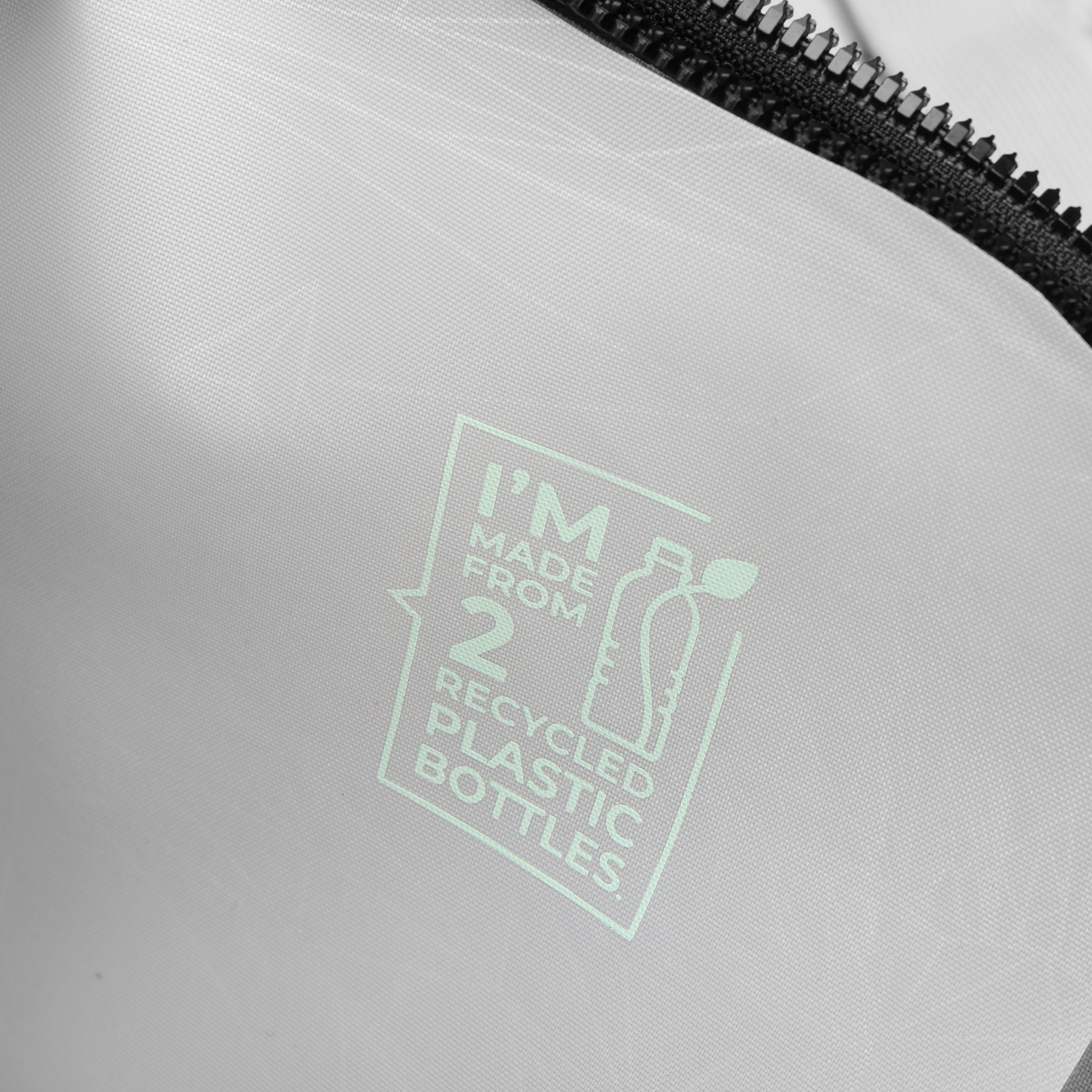 Primo piano di una borsa con la scritta 'I'M MADE FROM 2 RECYCLED PLASTIC BOTTLES' e una cerniera.