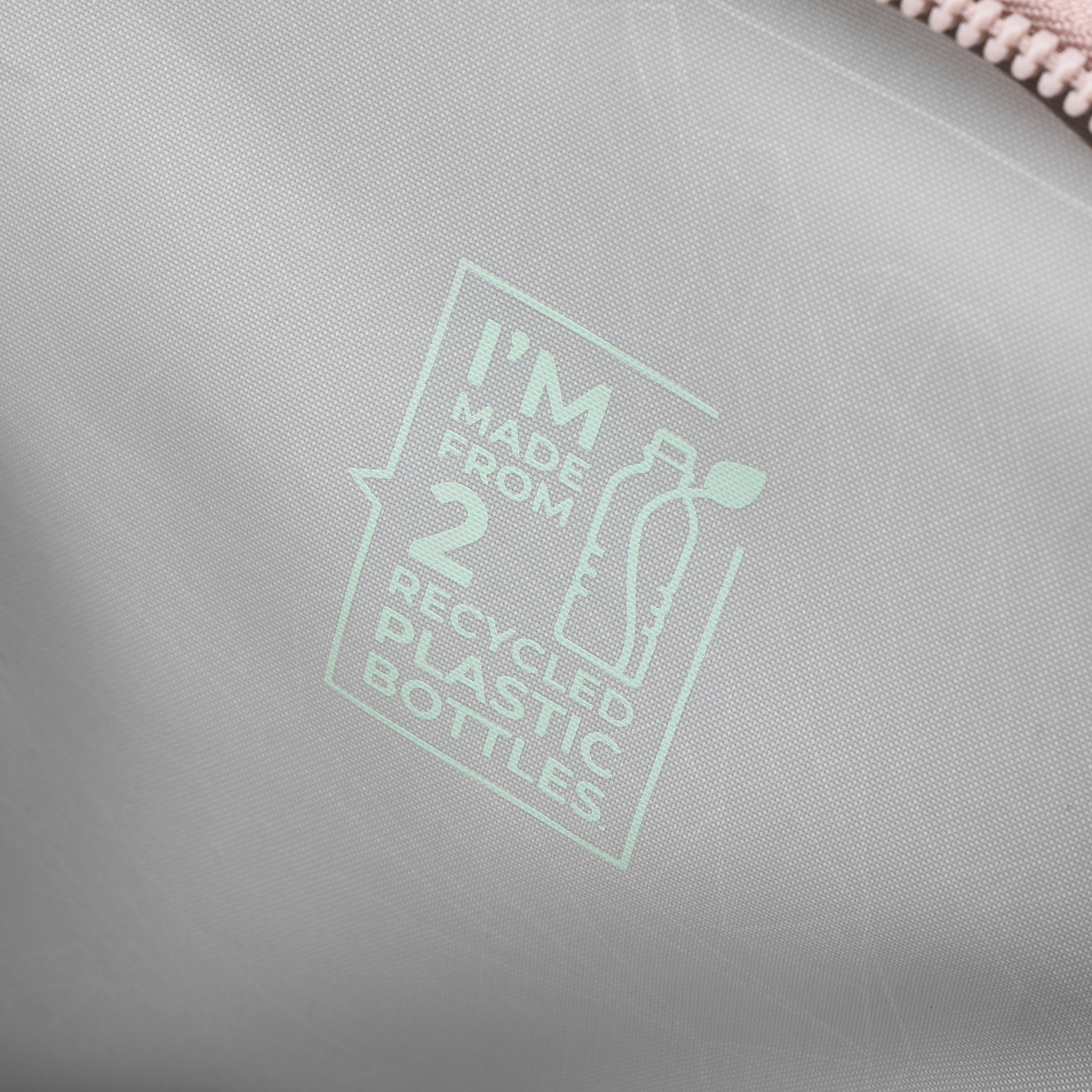Primo piano di una superficie grigio chiaro con una grafica verde che recita 'Sono fatto da 2 bottiglie di plastica riciclate'.
