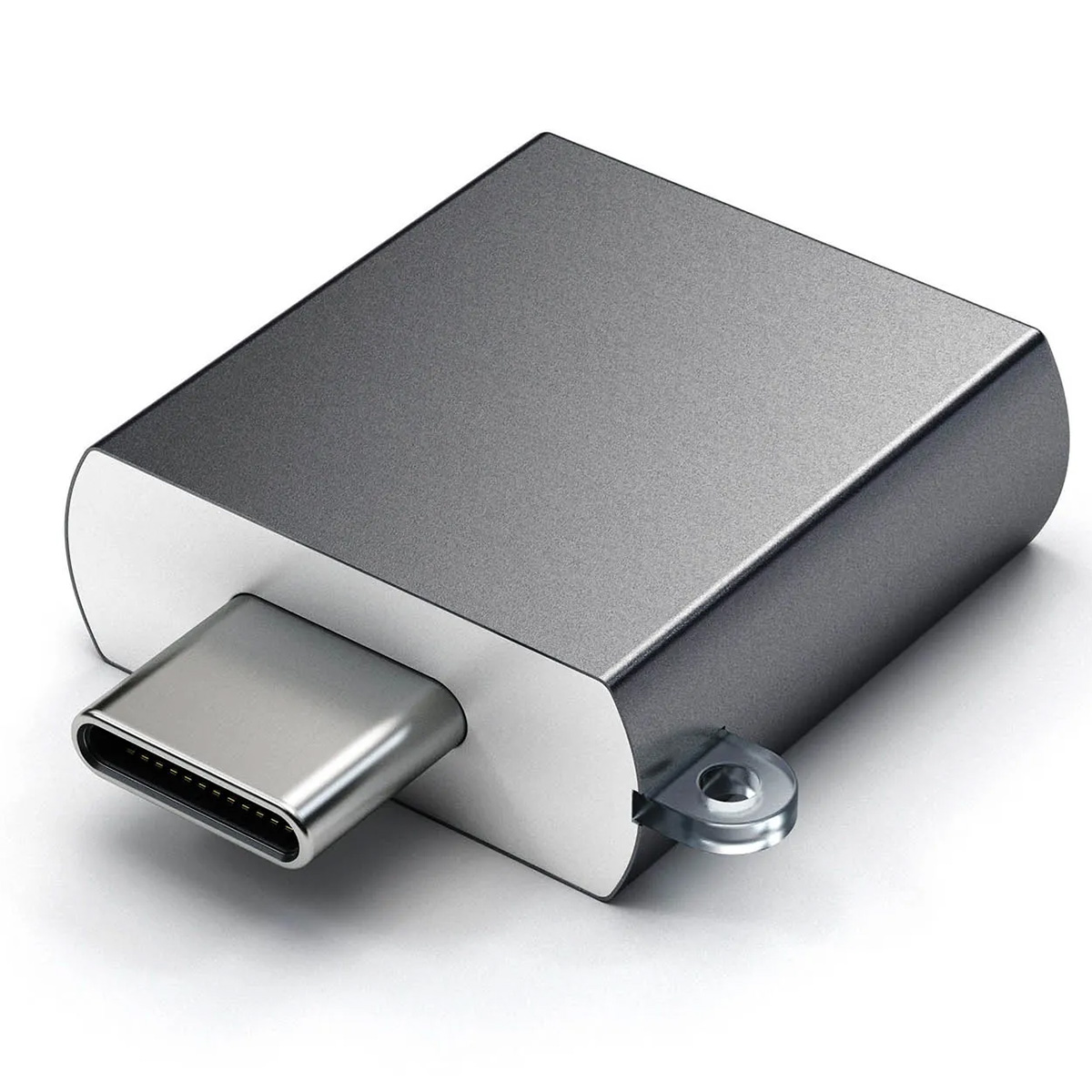 Szara przejściówka USB-C leży na białej powierzchni. Ma metalowe złącze USB-C. Urządzenie ma prostokątny kształt z zaokrąglonymi rogami.