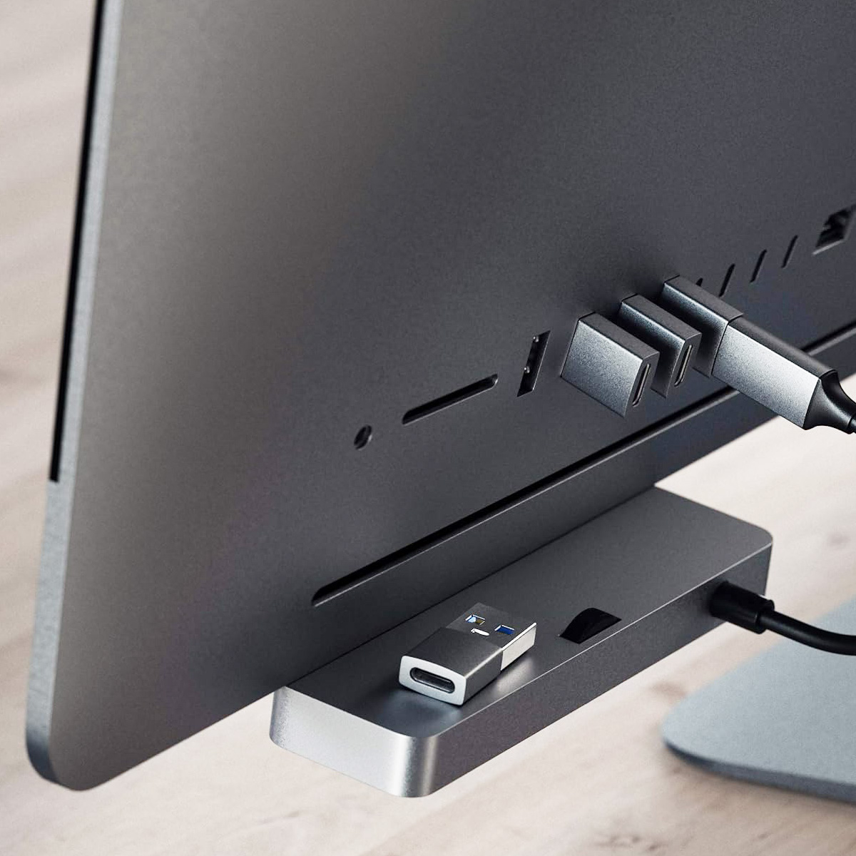 Un monitor del computer con un hub USB collegato. Un adattatore USB-C e altre spine sono collegati. L'impostazione è grigio metallizzato.