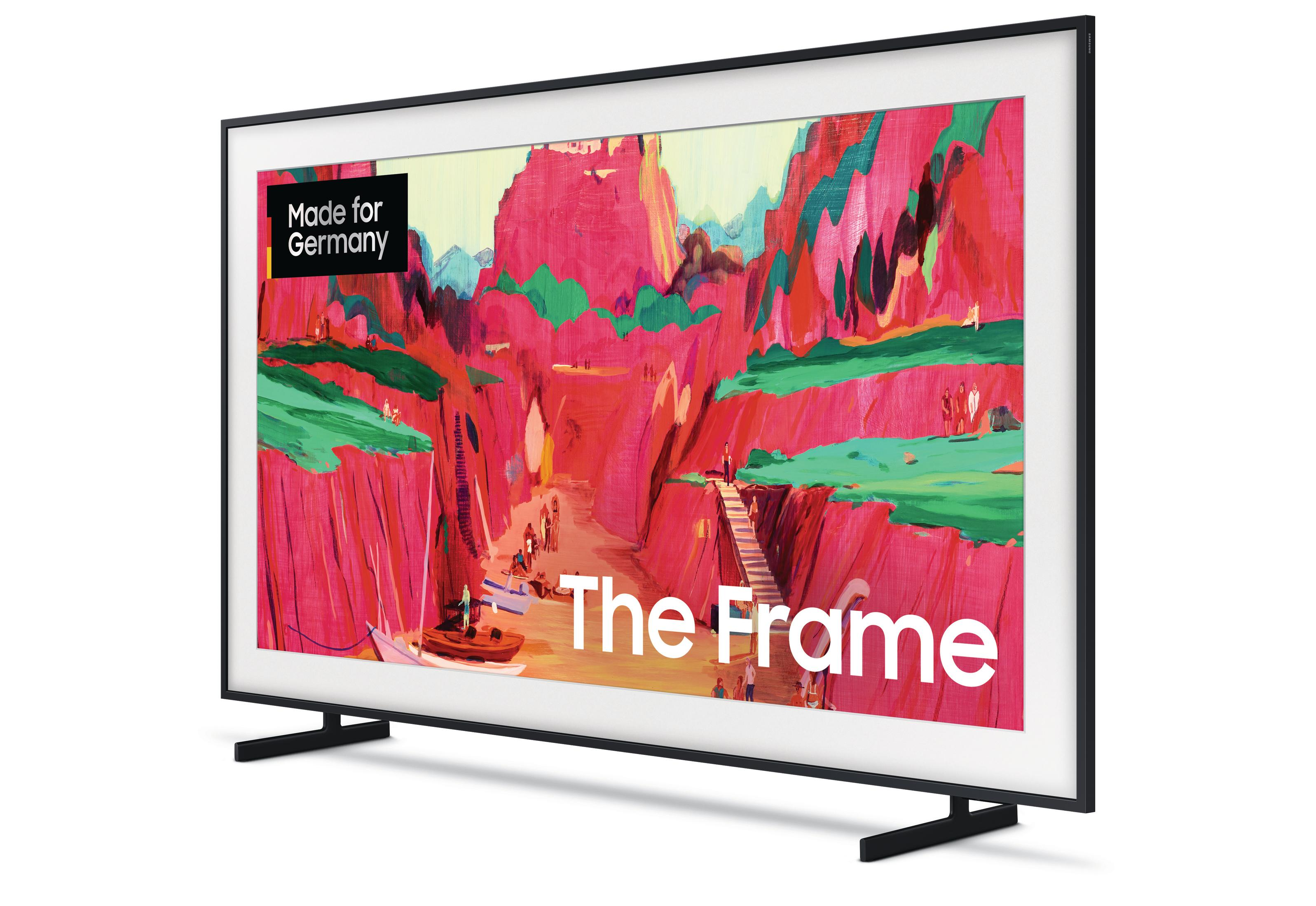 Telewizor Samsung 'The Frame' wyświetla kolorowy obraz sceny kanionu. Telewizor stoi na stojaku, a ramka jest czarna.