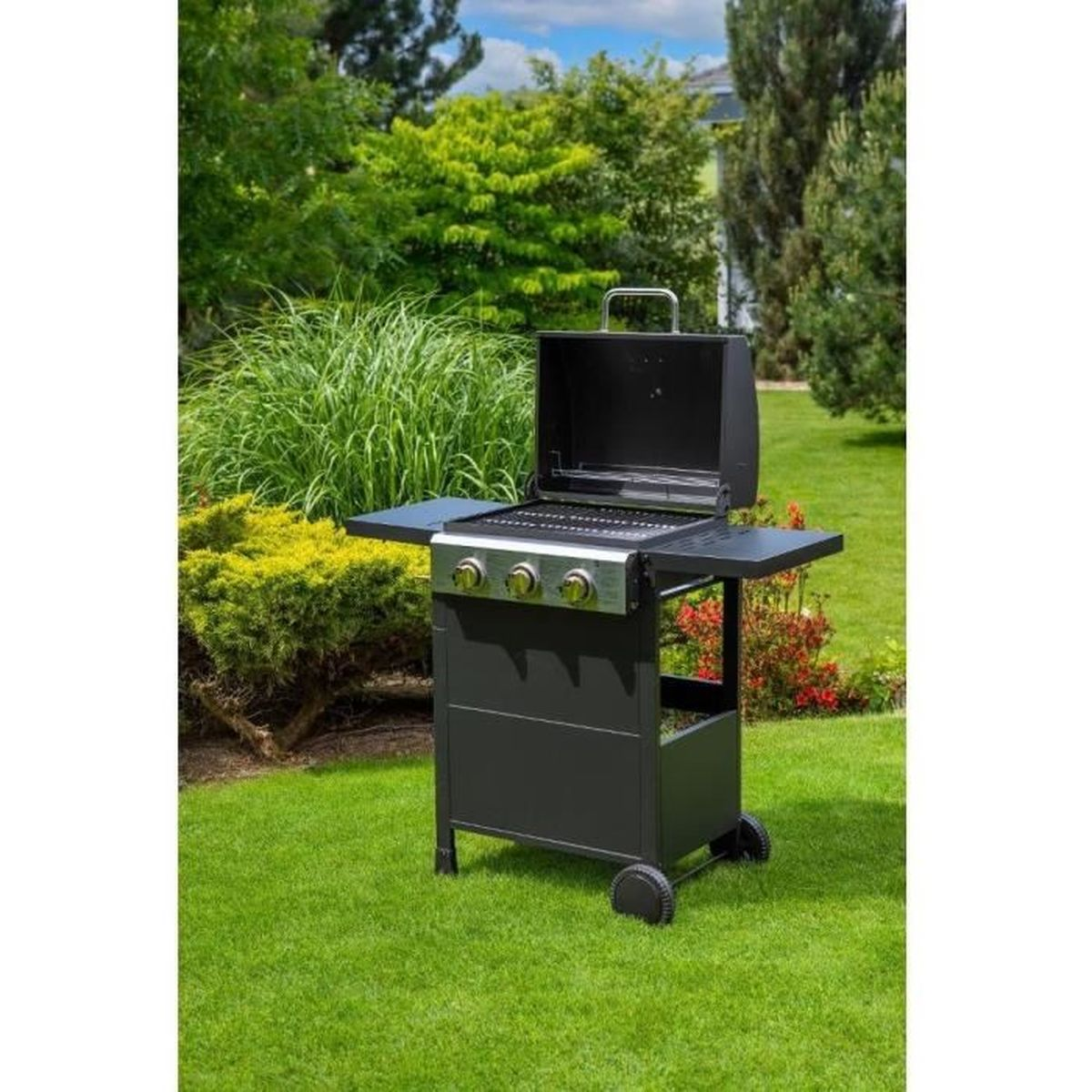 Ein schwarzer Grill mit geöffnetem Deckel steht auf einem grünen Rasen. Bäume und Büsche sind im Hintergrund. Der Himmel ist blau.
