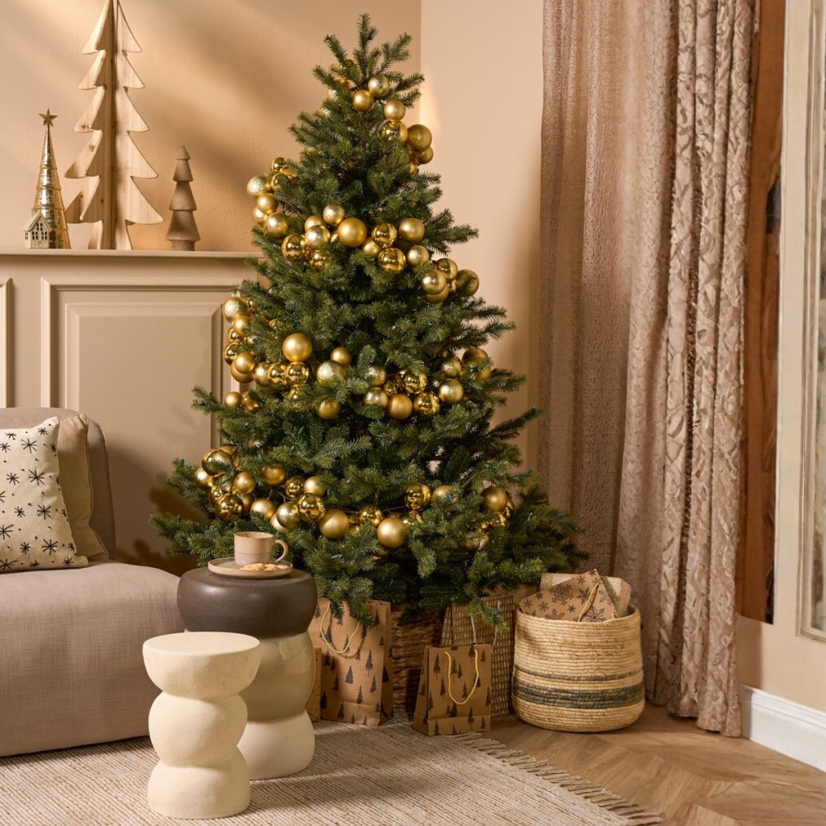 A decorated Christmas tree with golden ornaments stands in a room. Gifts, a rug, and a beige sofa are visible. A cup of coffee on a side table.