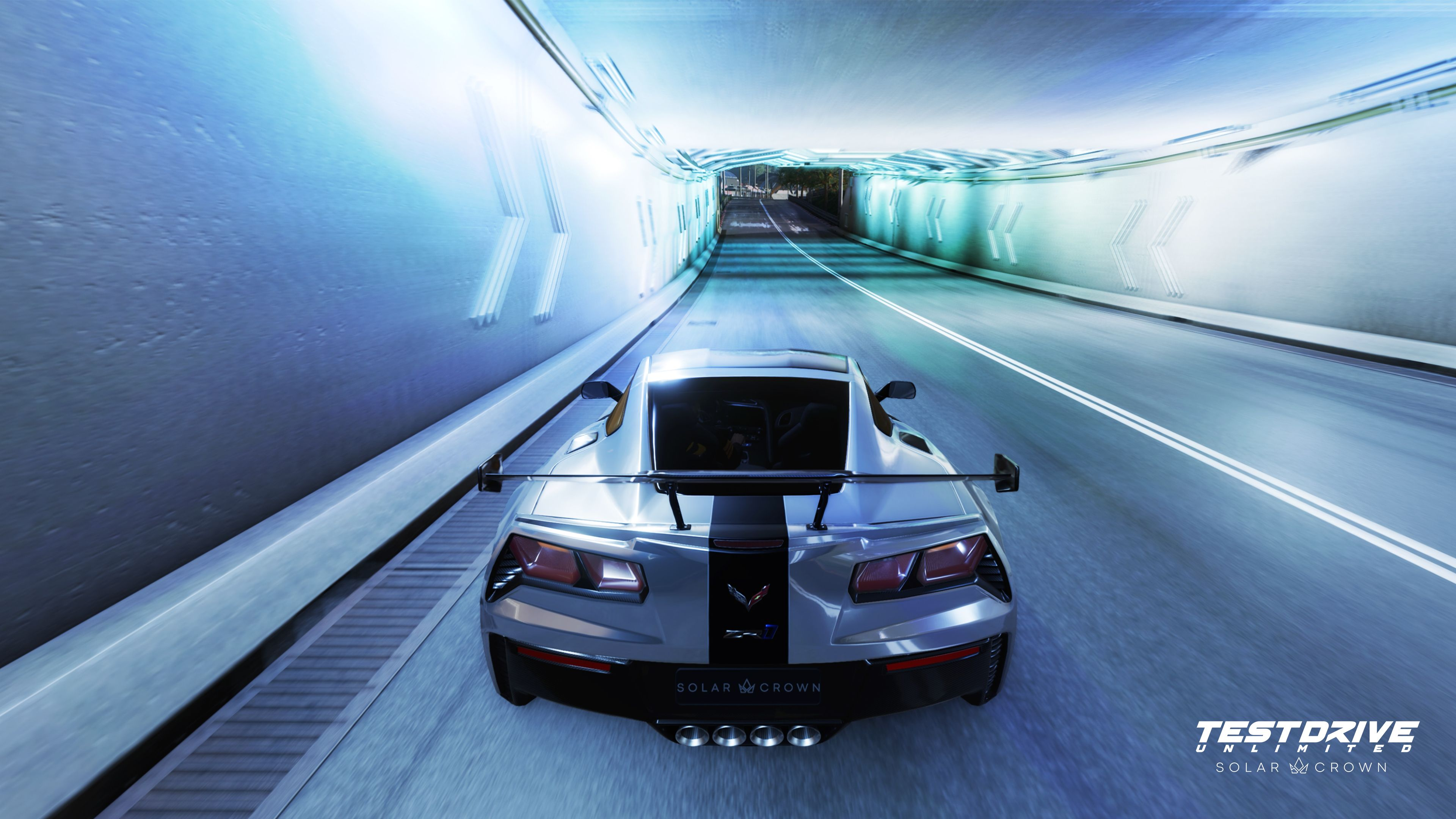 Un'auto sportiva argentata sfreccia in un tunnel. L'auto ha una striscia nera. Il tunnel è blu e bianco con frecce direzionali.