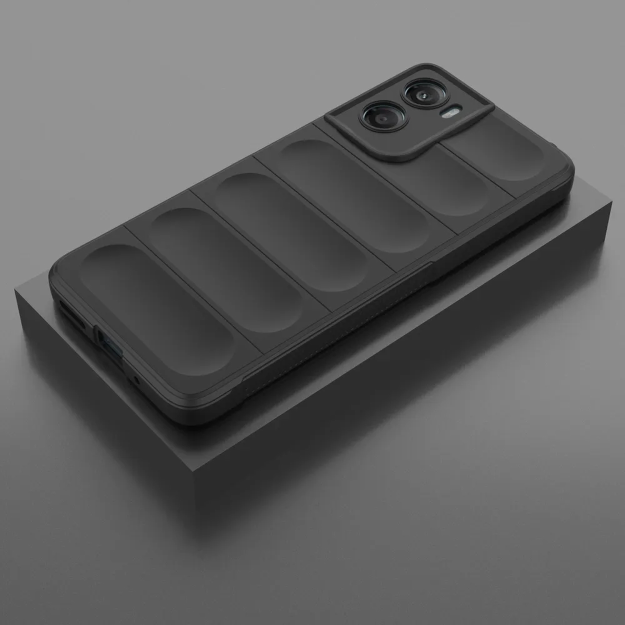 Un étui de téléphone noir avec une bosse de caméra repose sur une plateforme noire sur fond gris. L'étui a un design texturé.