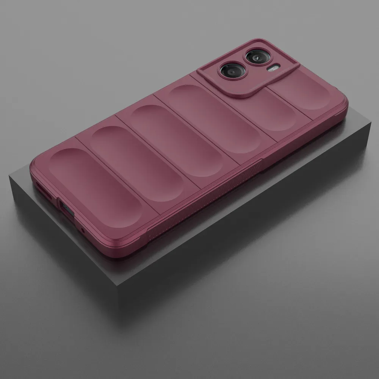 Une coque de téléphone bordeaux avec une bosse pour l'appareil photo repose sur un bloc gris. La coque a un dos texturé avec des rainures.