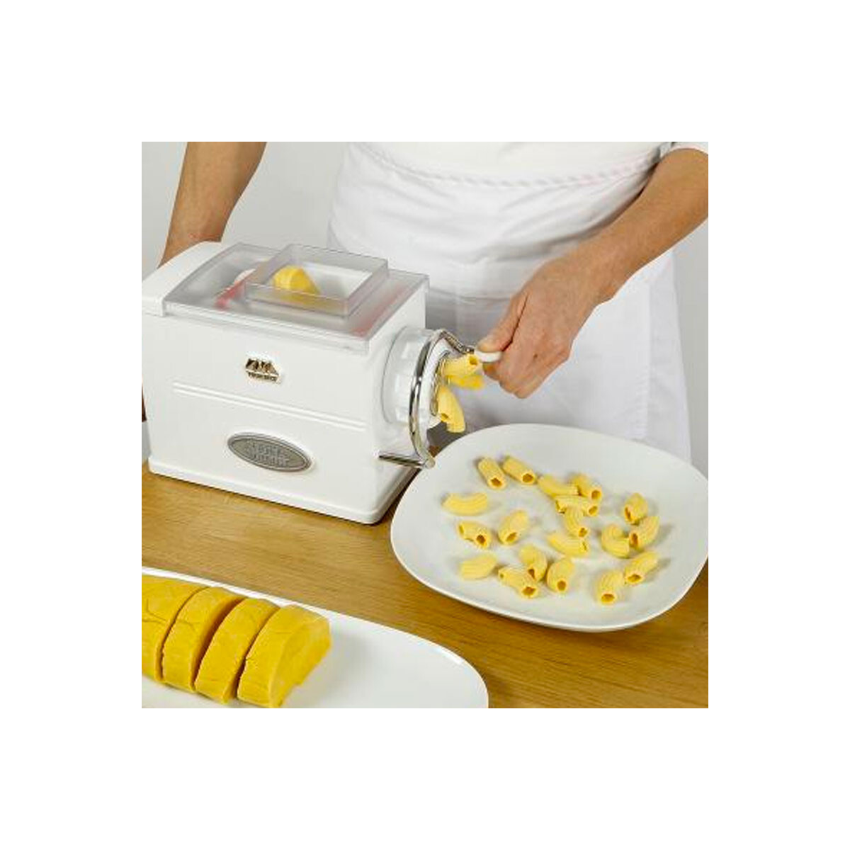 Eine Person benutzt eine Pastamaschine. Frische Pasta wird hergestellt. Gelbe Pasta auf Tellern.
