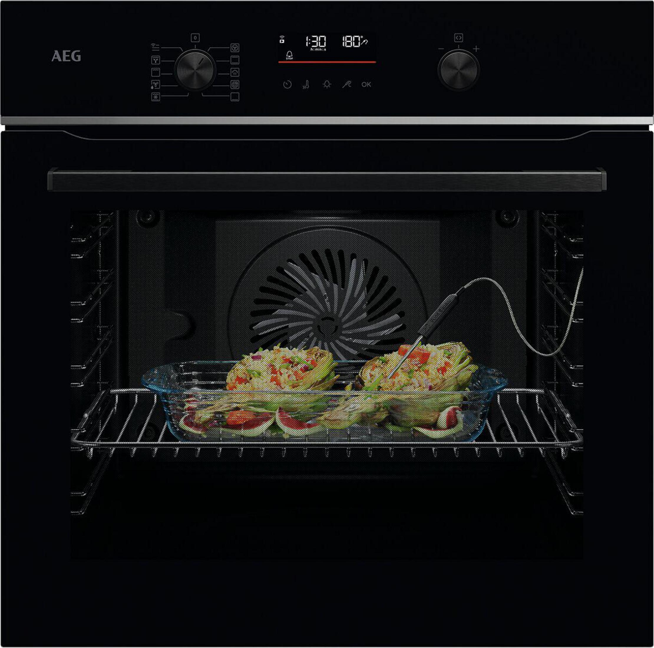 Ein Backofen mit Essen. Die Anzeige zeigt Zeit und Temperatur. Ein Glasbehälter hält Speisen auf dem Rost.