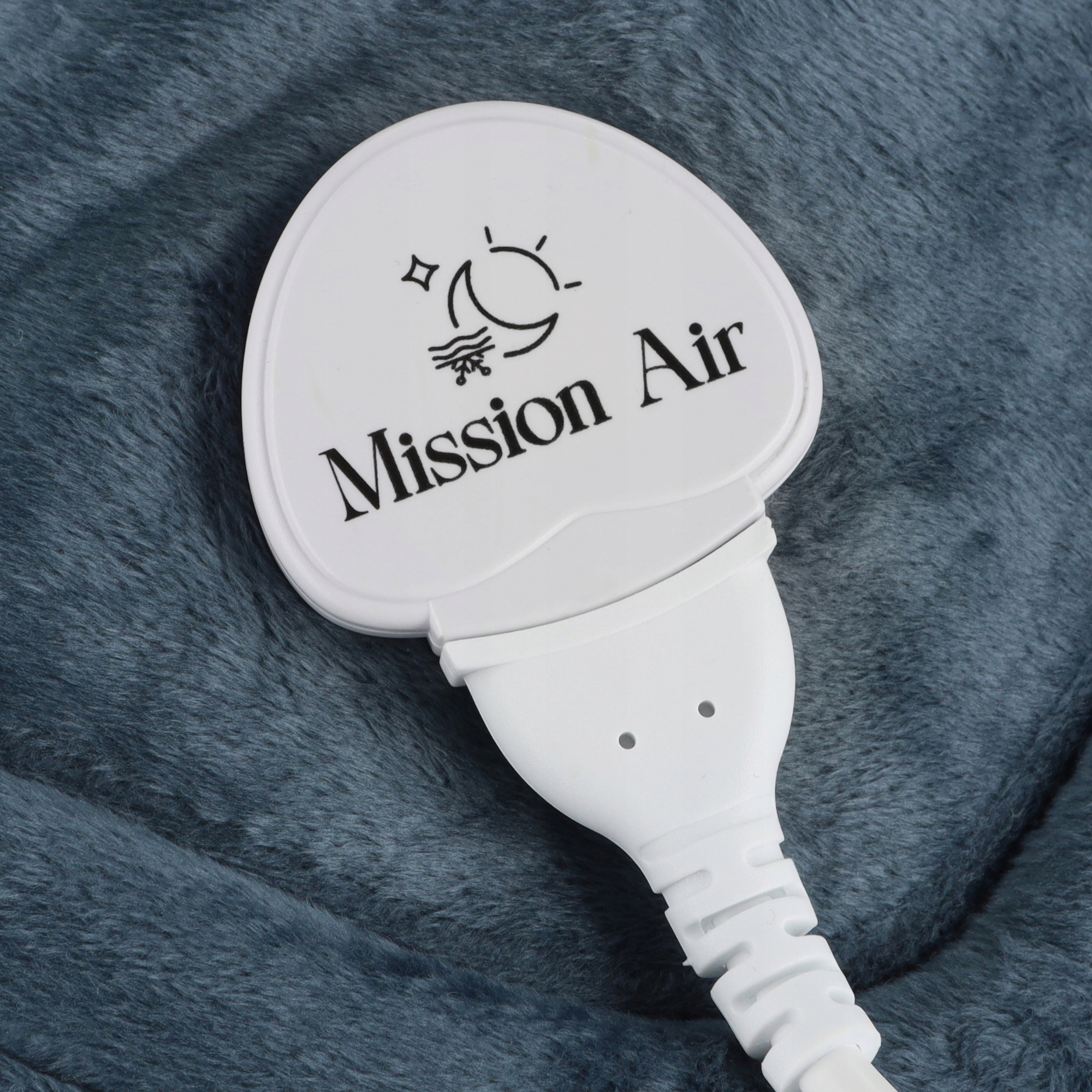 Biały panel sterowania z napisem "Mission Air" i symbolem, na niebiesko-szarej, puszystej powierzchni.